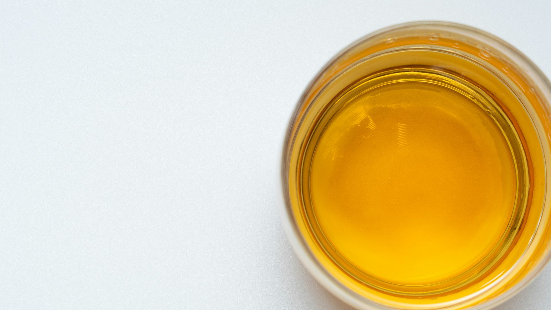 a glass filled with yellow liquid on top of a white table