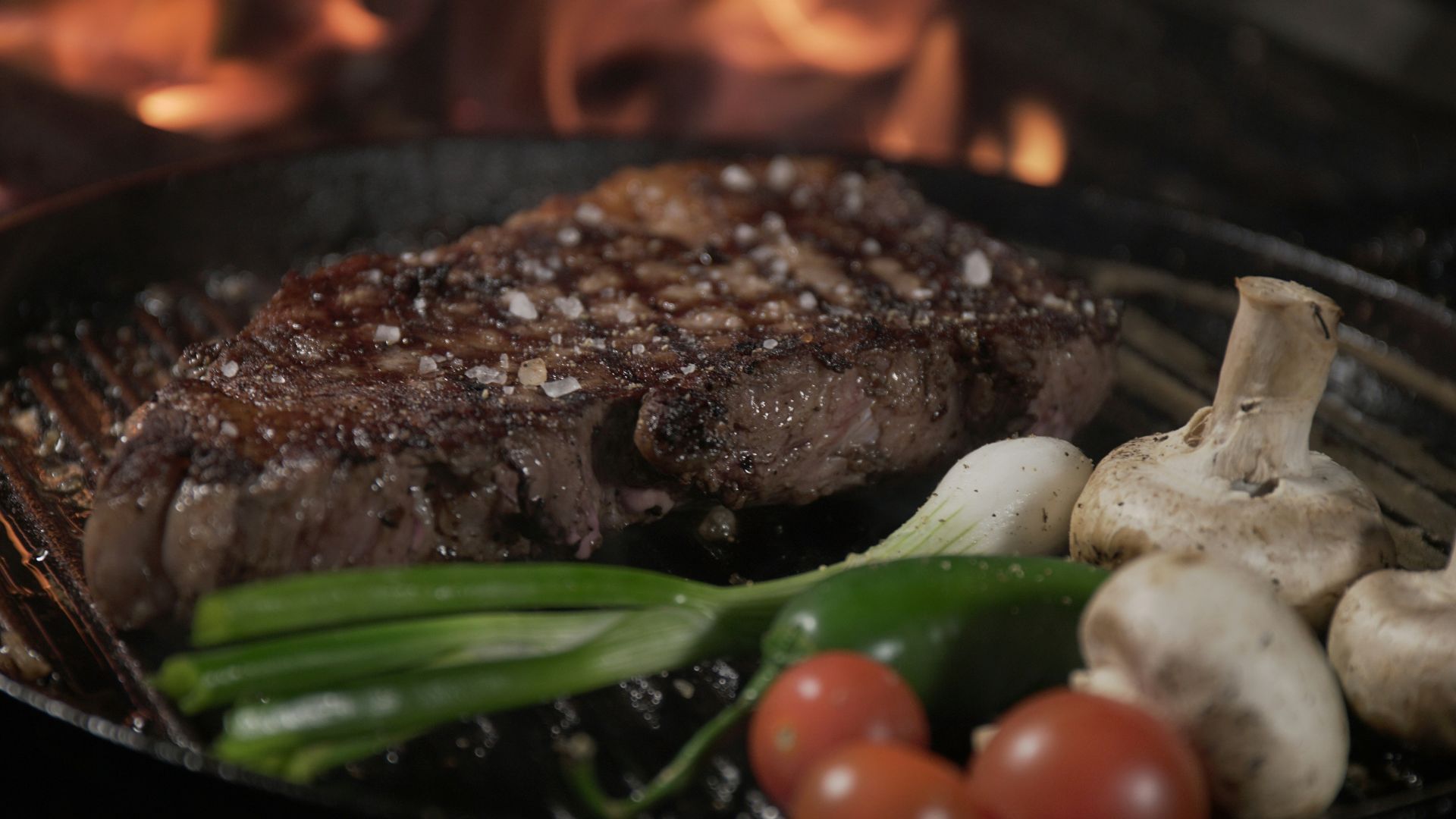 a steak and vegetables cooking on a grill