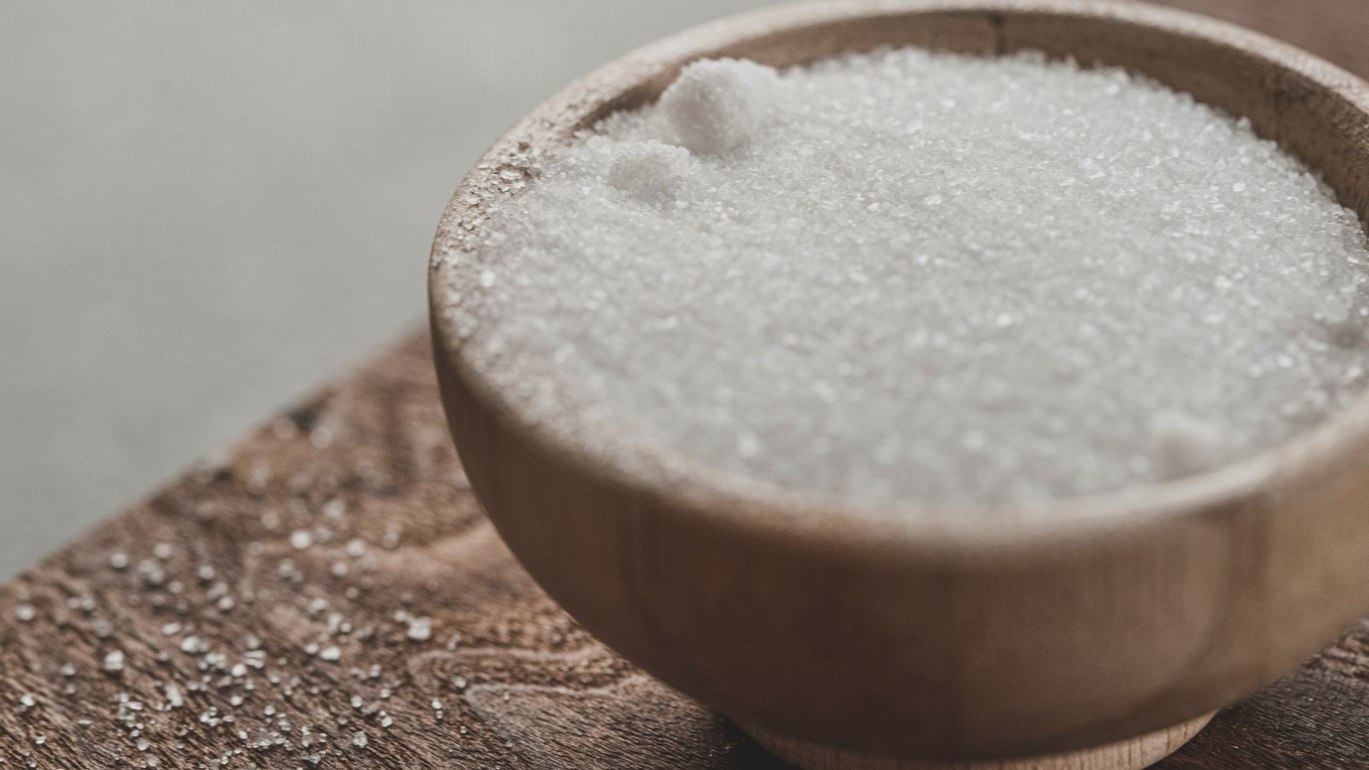 a wooden bowl filled with sugar on top of a wooden table
