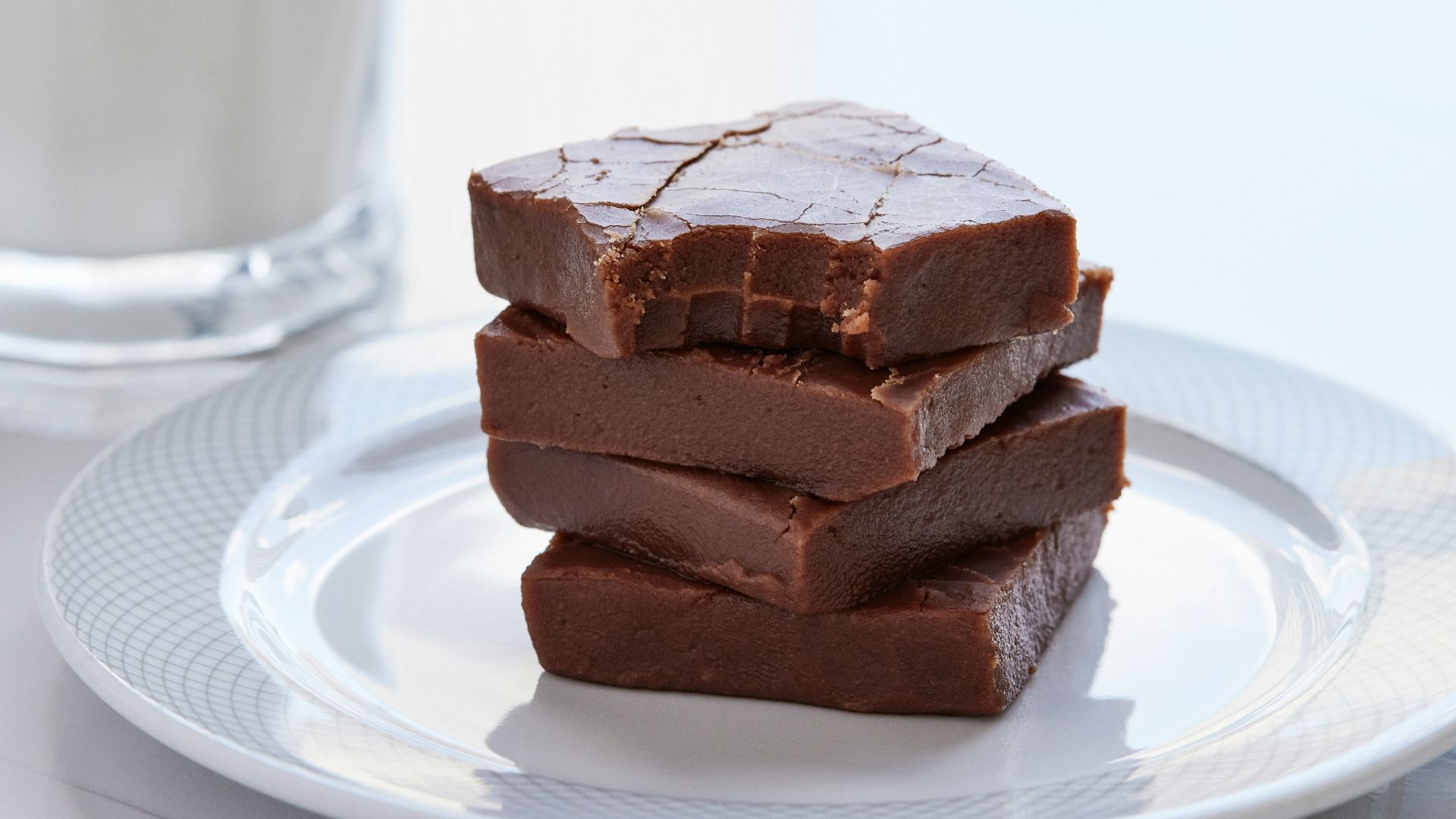three pieces of chocolate on a plate next to a glass of milk