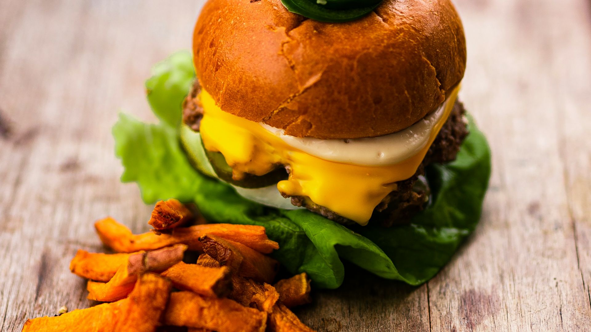 burger with lettuce and fries on brown wooden table