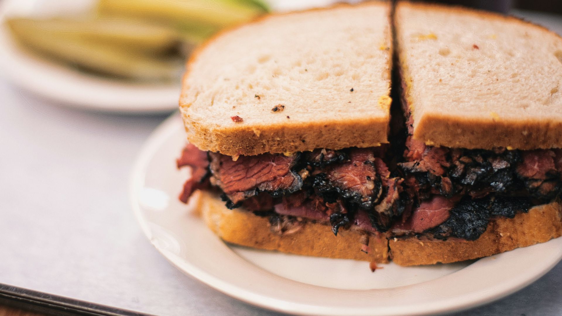 a roast beef sandwich on a plate with pickles
