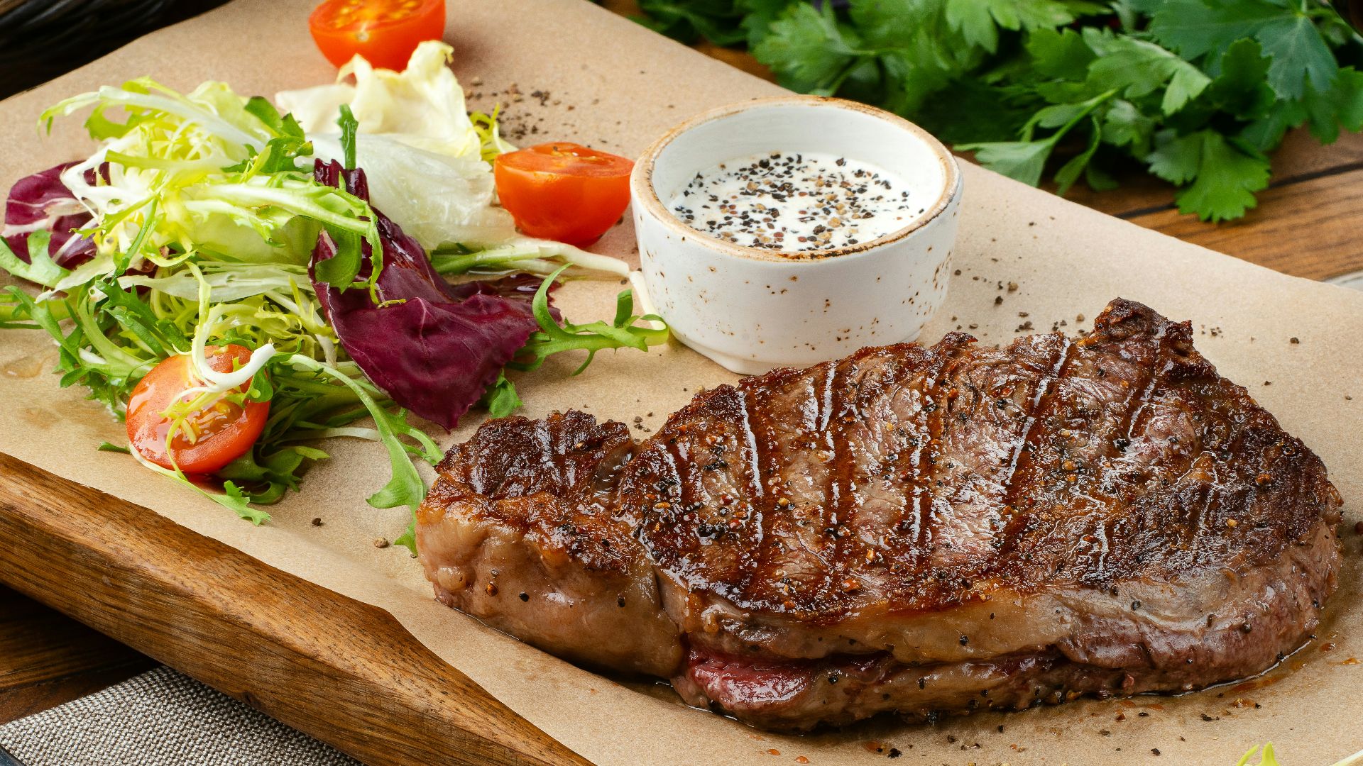a steak with a side of salad and a glass of wine