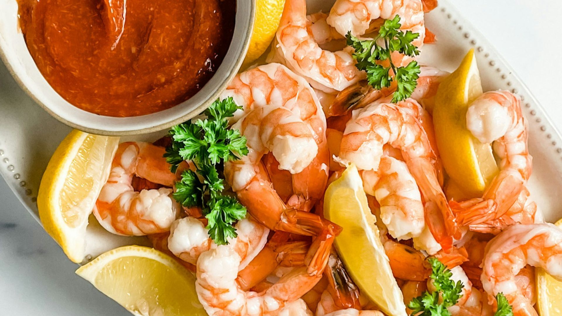a plate of shrimp and lemons with a dipping sauce