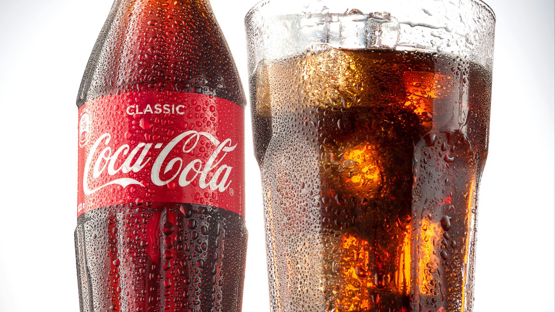 coca cola bottle beside drinking glass