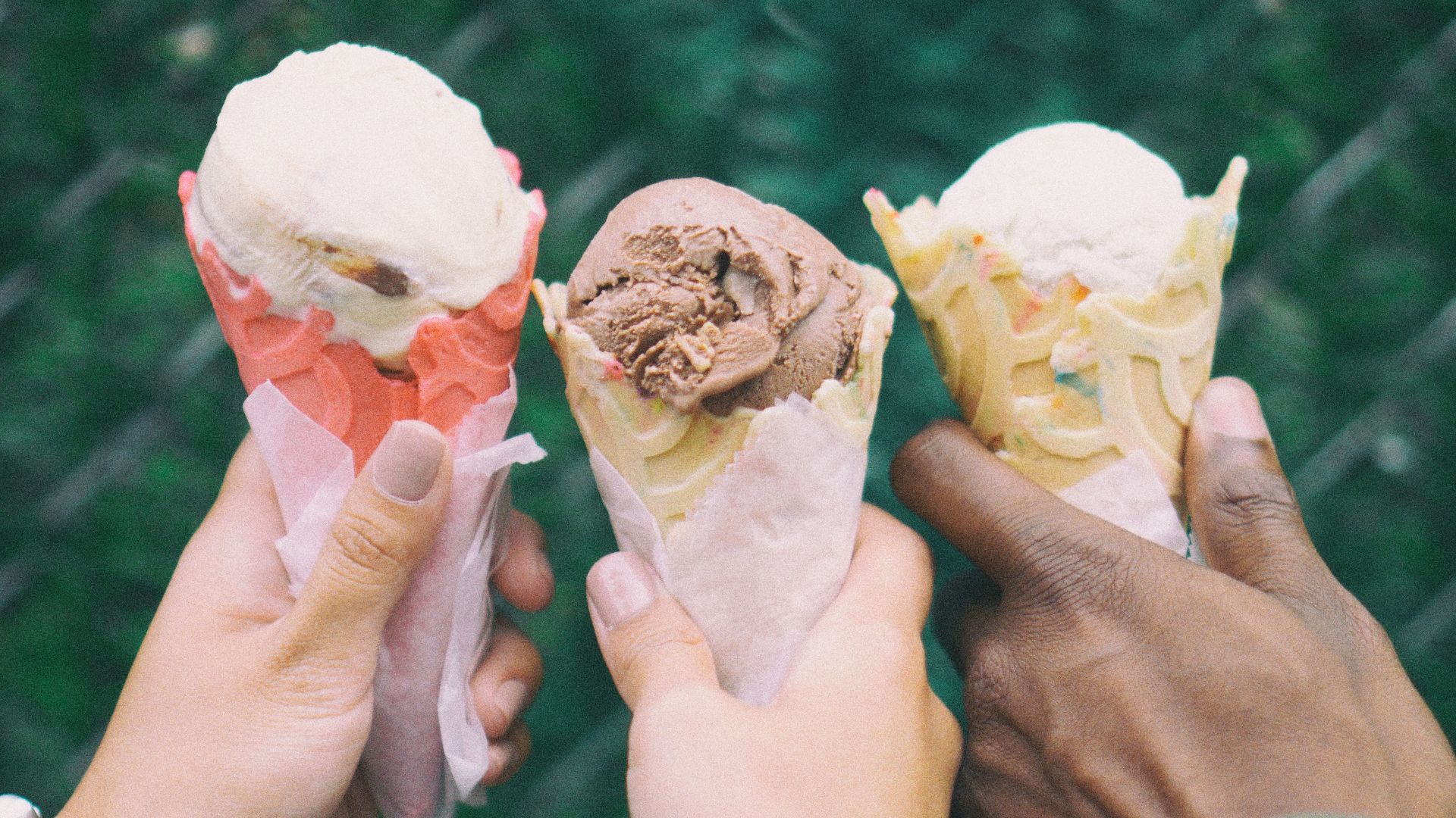 three people holding ice cream cones in their hands