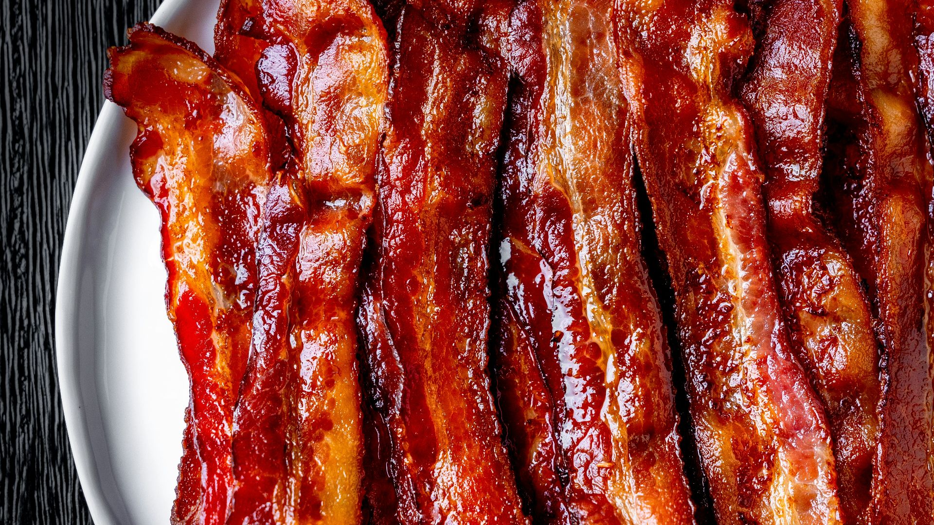 a white plate topped with bacon strips on top of a table