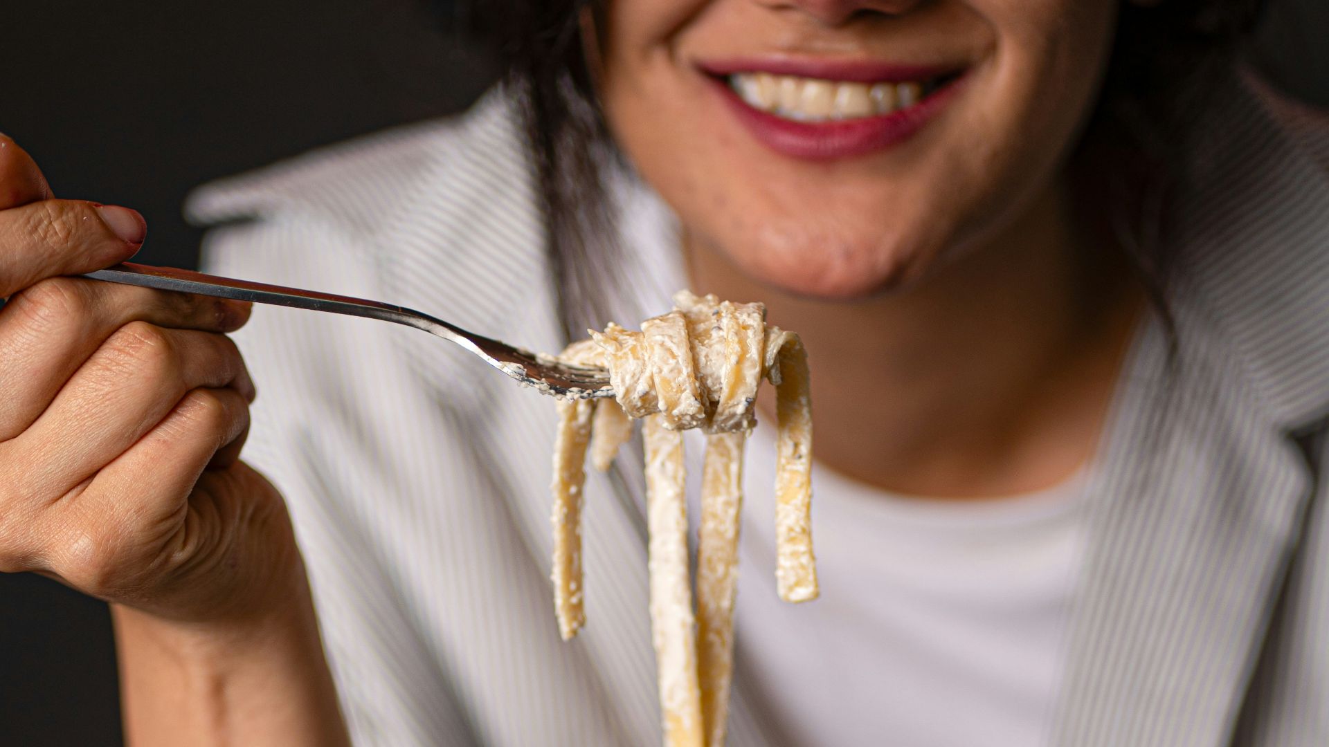 Woman happily eating pasta from a plate.