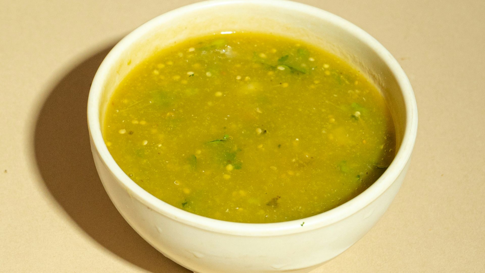A white bowl filled with green soup on top of a table