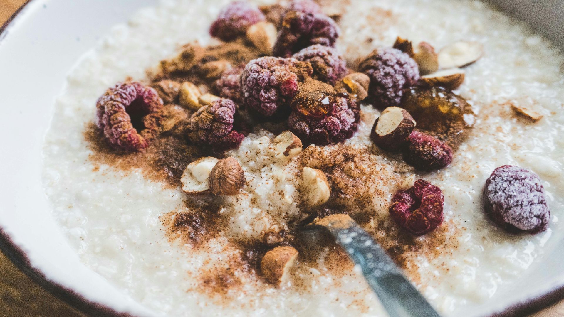 a bowl of oatmeal topped with nuts and raspberries