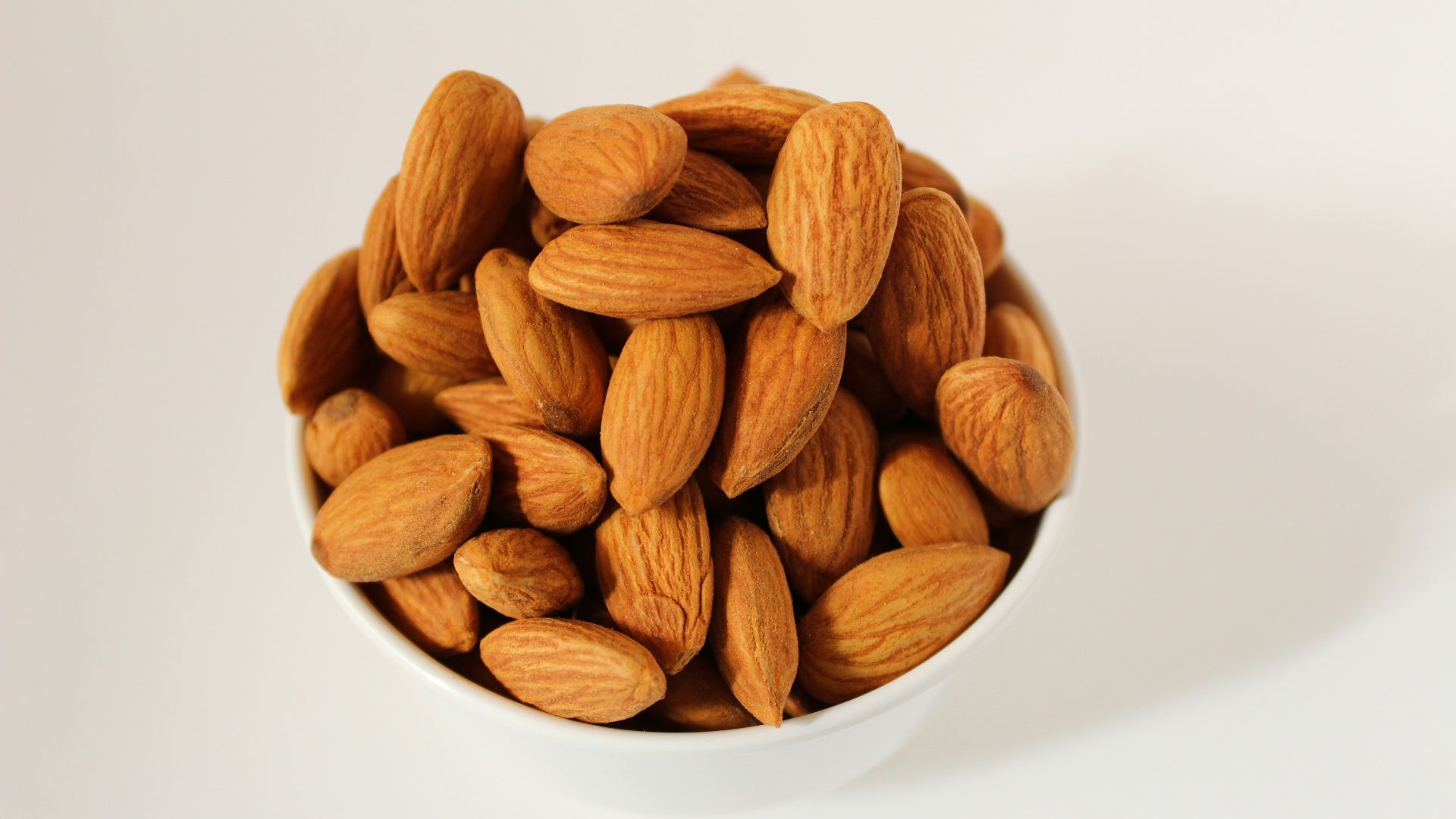 brown almond nuts on white ceramic bowl