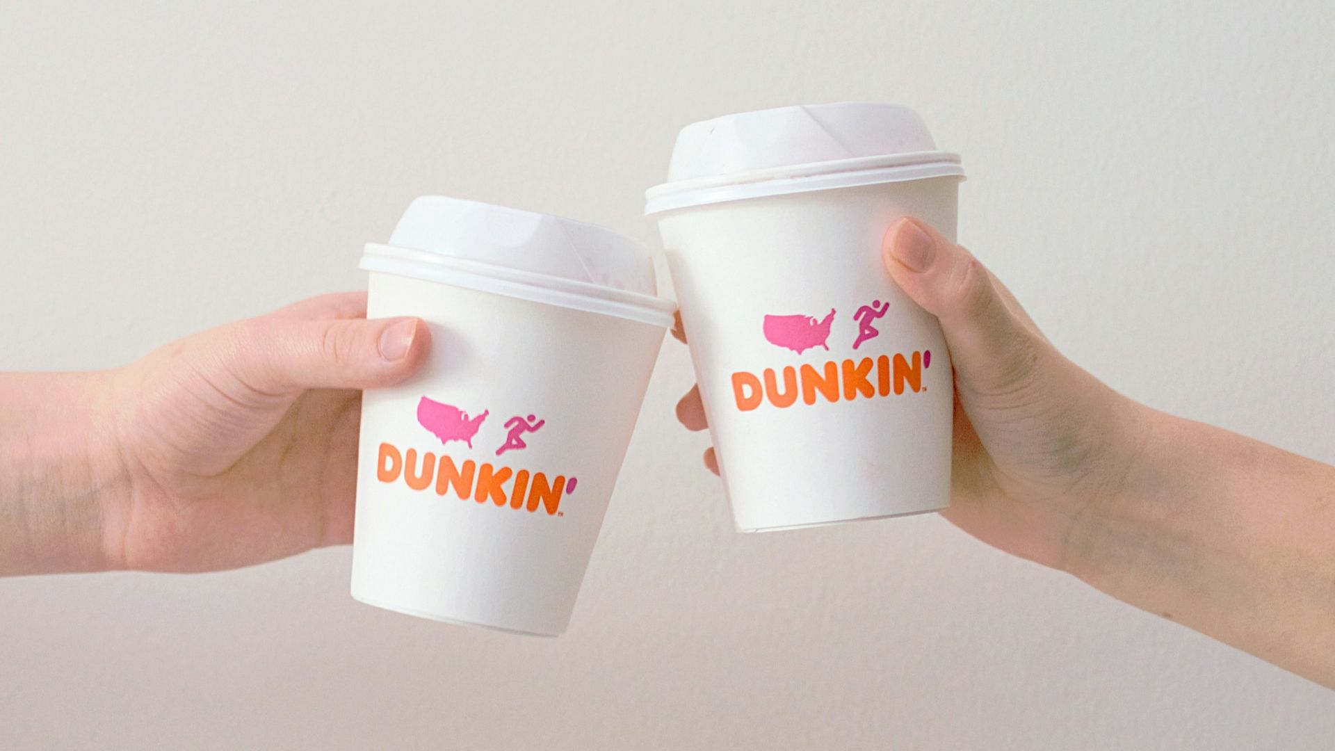 two people with white Dunkin' Donuts paper cups
