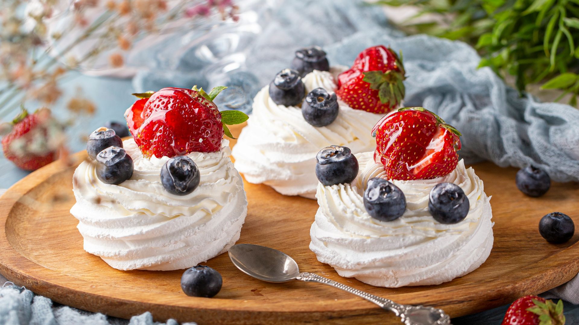 two desserts with strawberries and blueberries on a wooden platter