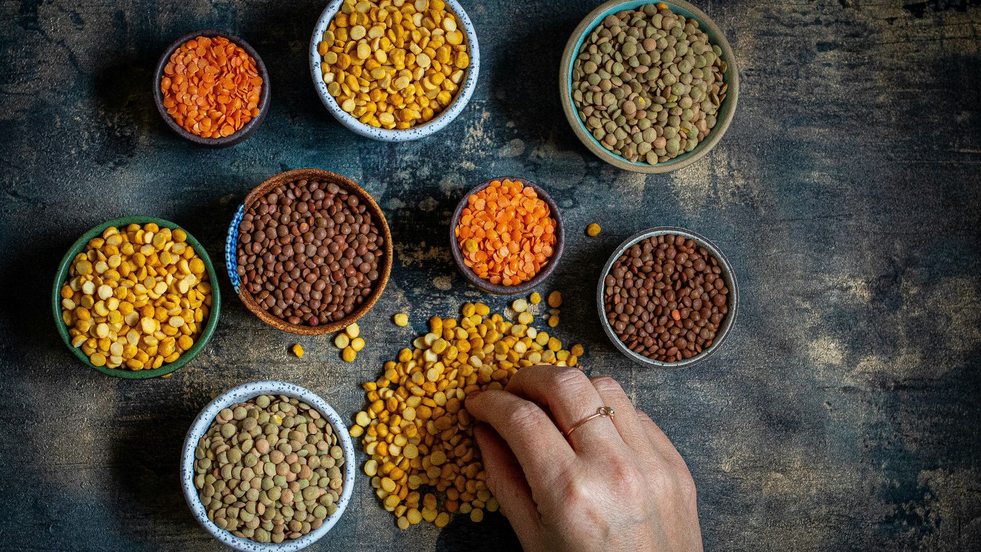 a person touching a bowl of lentils on a table