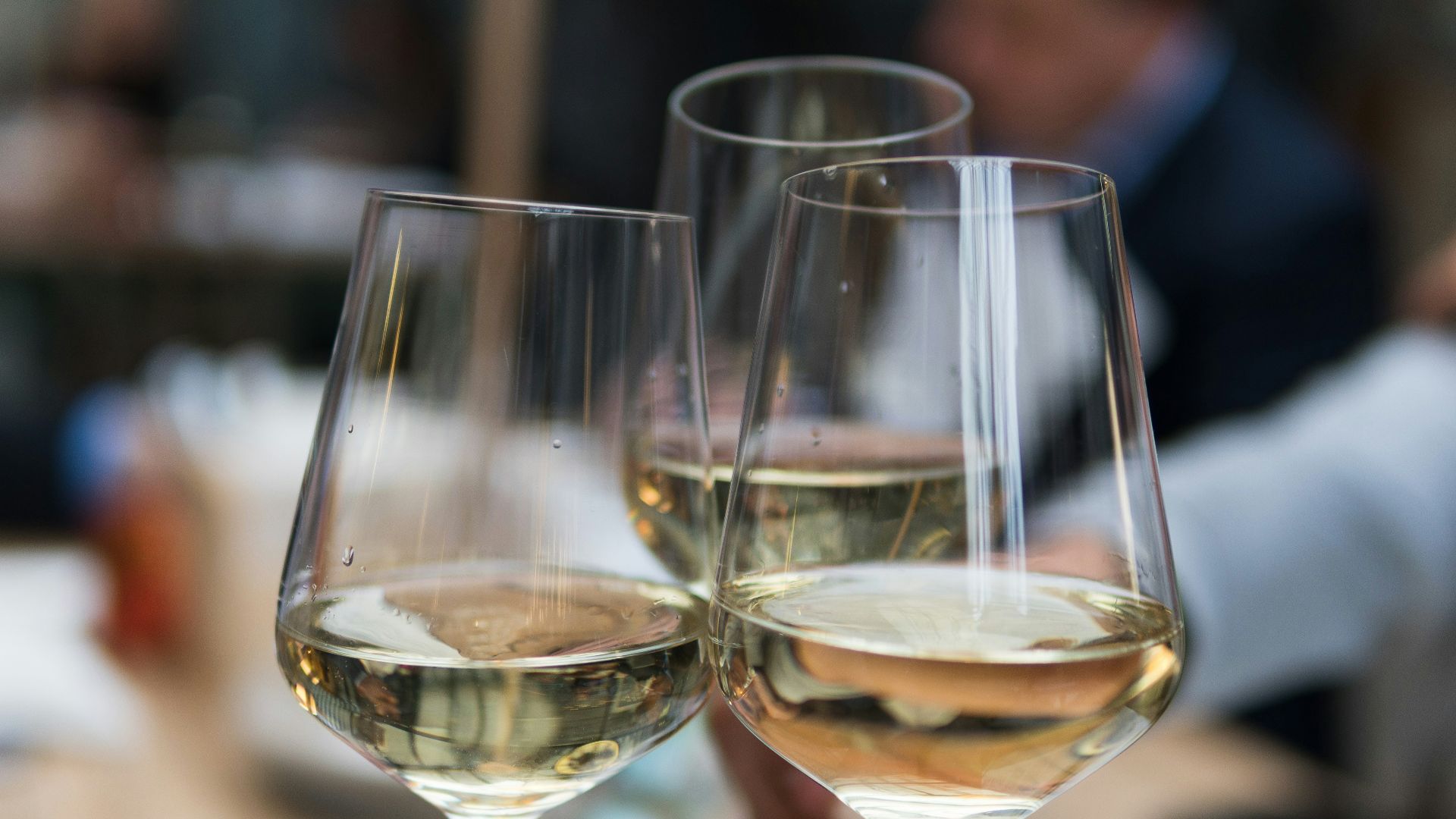 three people having a toast using three clear crystal wine glasses