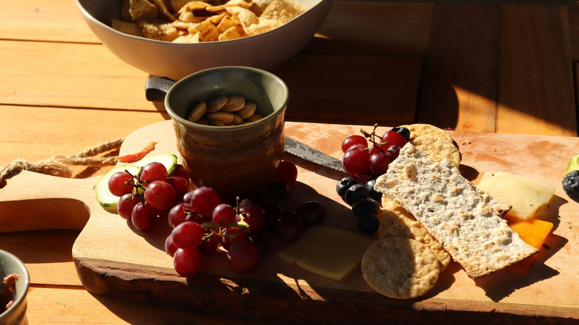 a wooden cutting board topped with grapes and crackers