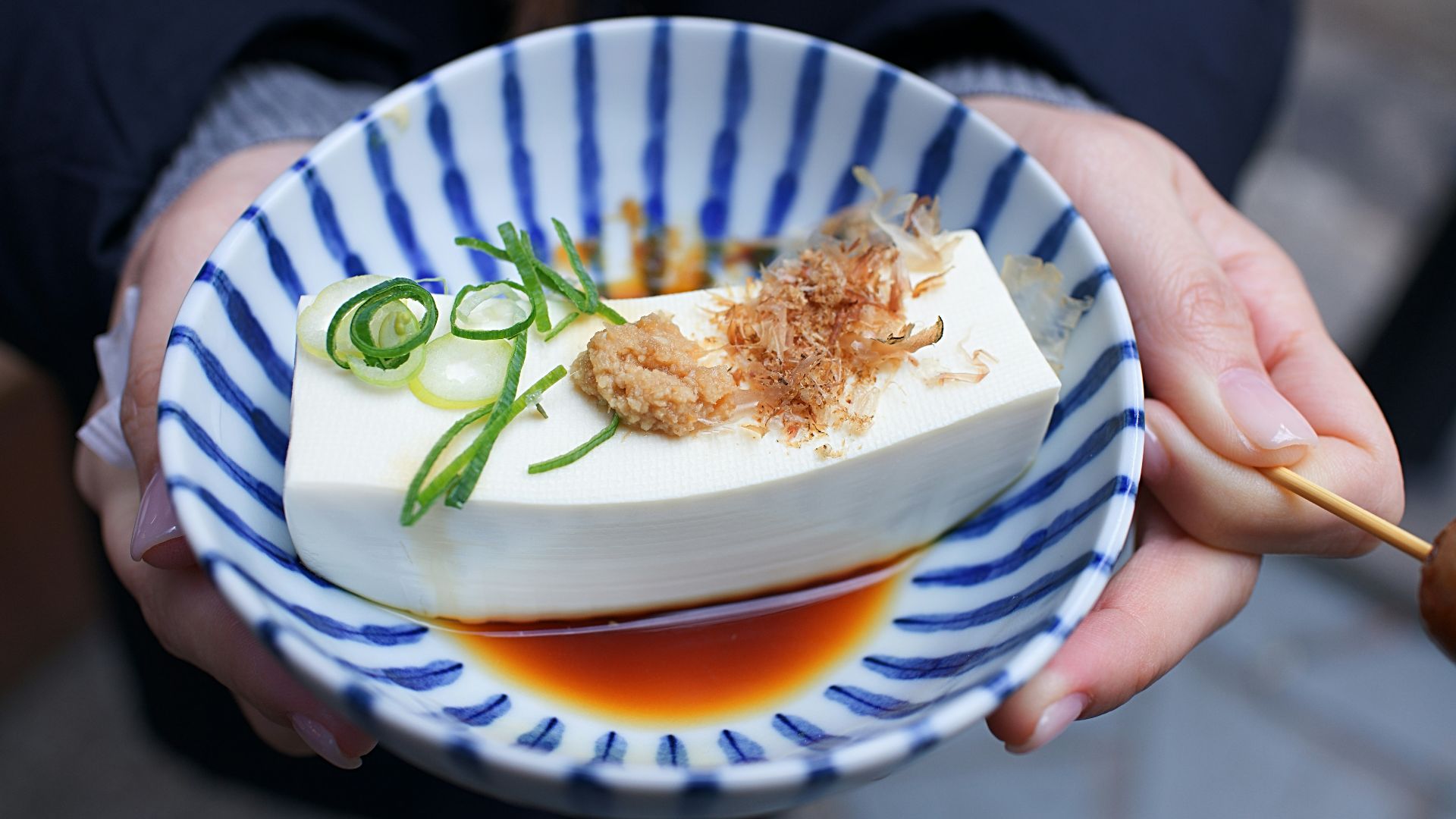 person holding white and blue ceramic plate with rice and sliced cucumber