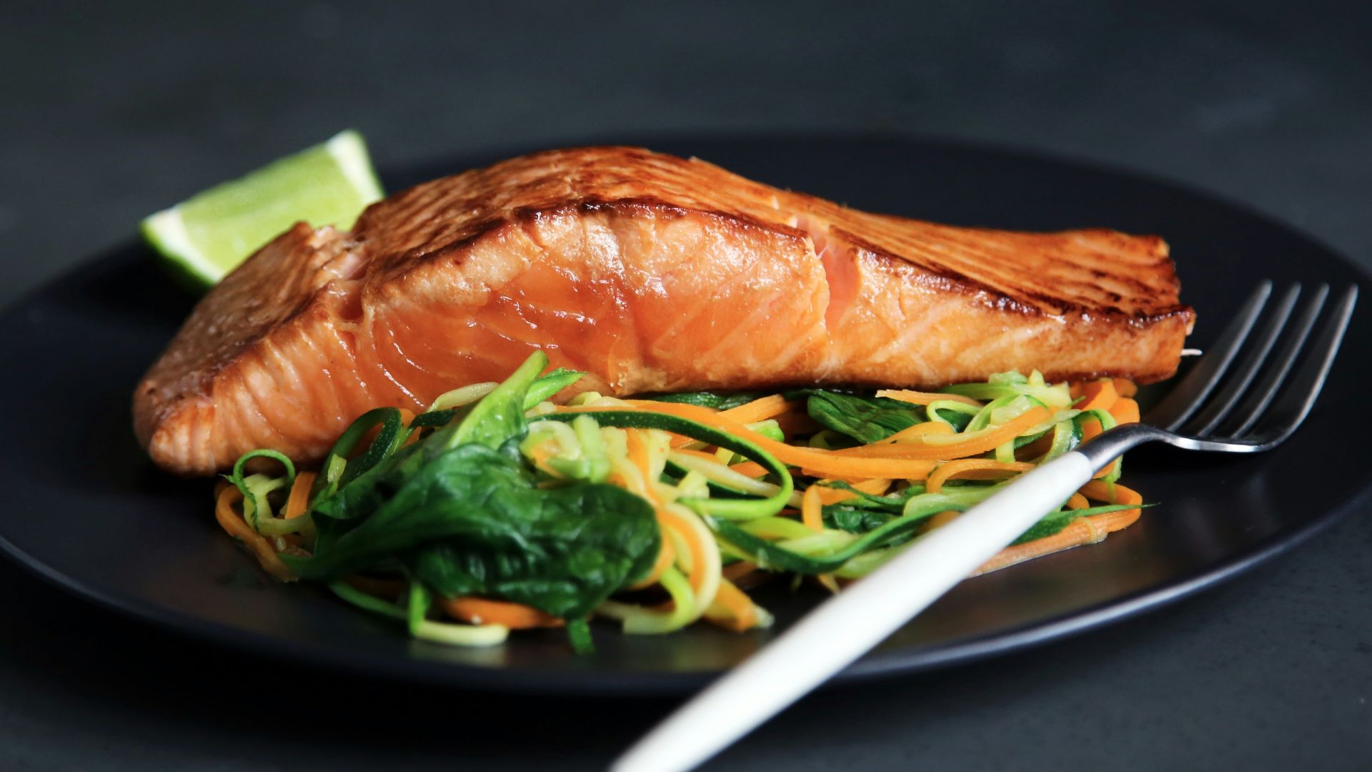 grilled fish, cooked vegetables, and fork on plate