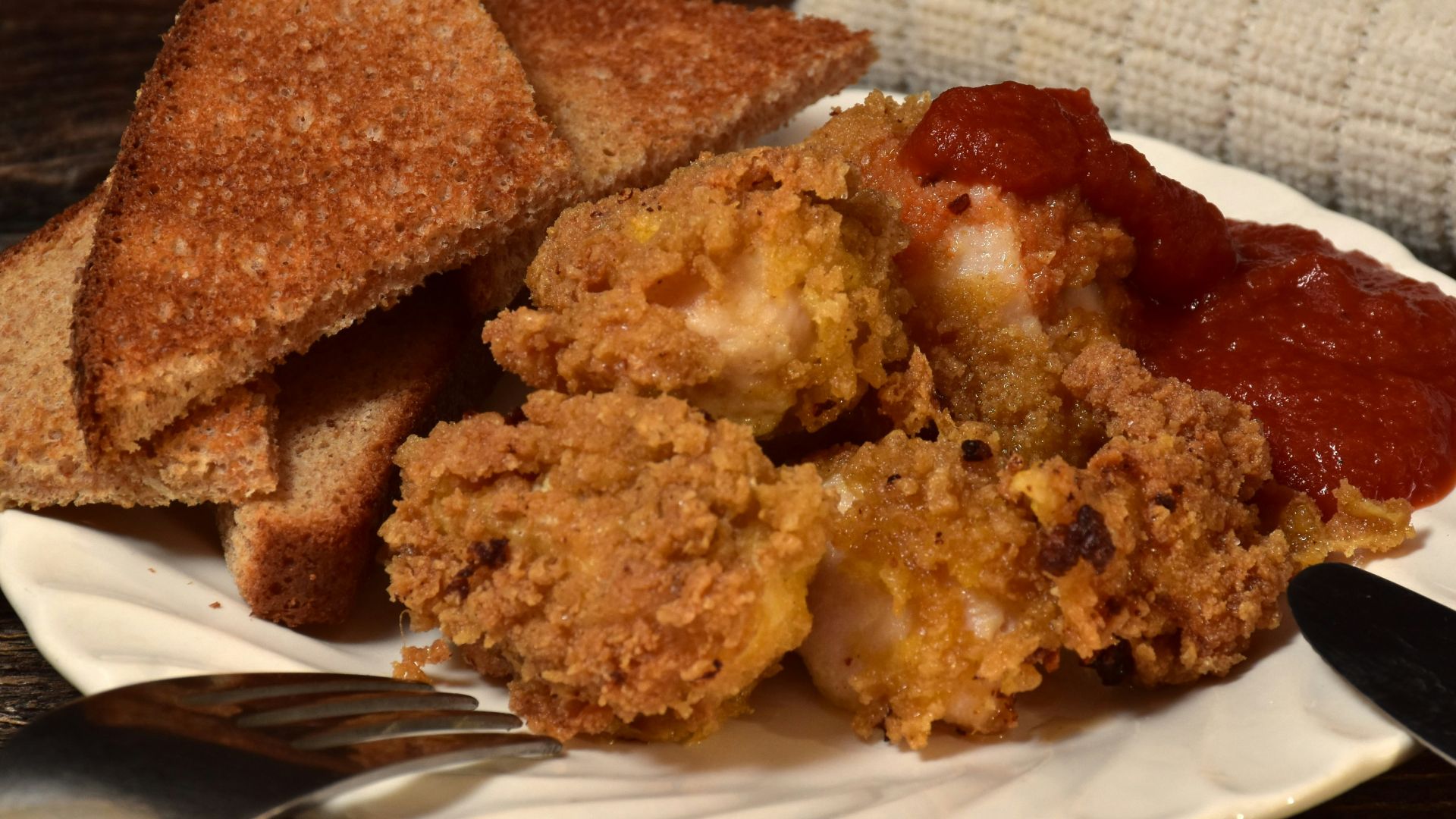 Fried chicken and toast on a plate with sauce.