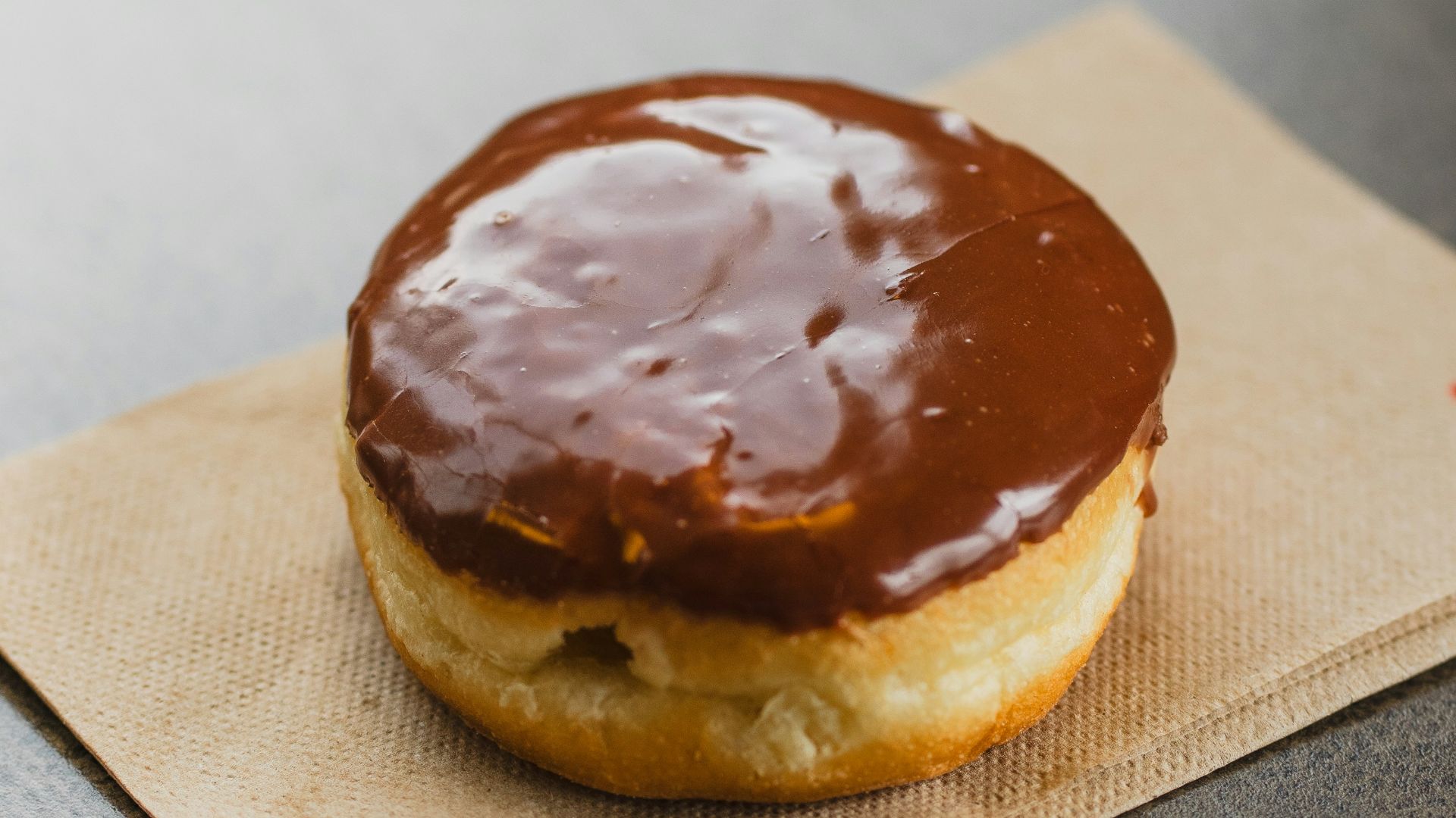 a chocolate covered doughnut sitting on top of a napkin