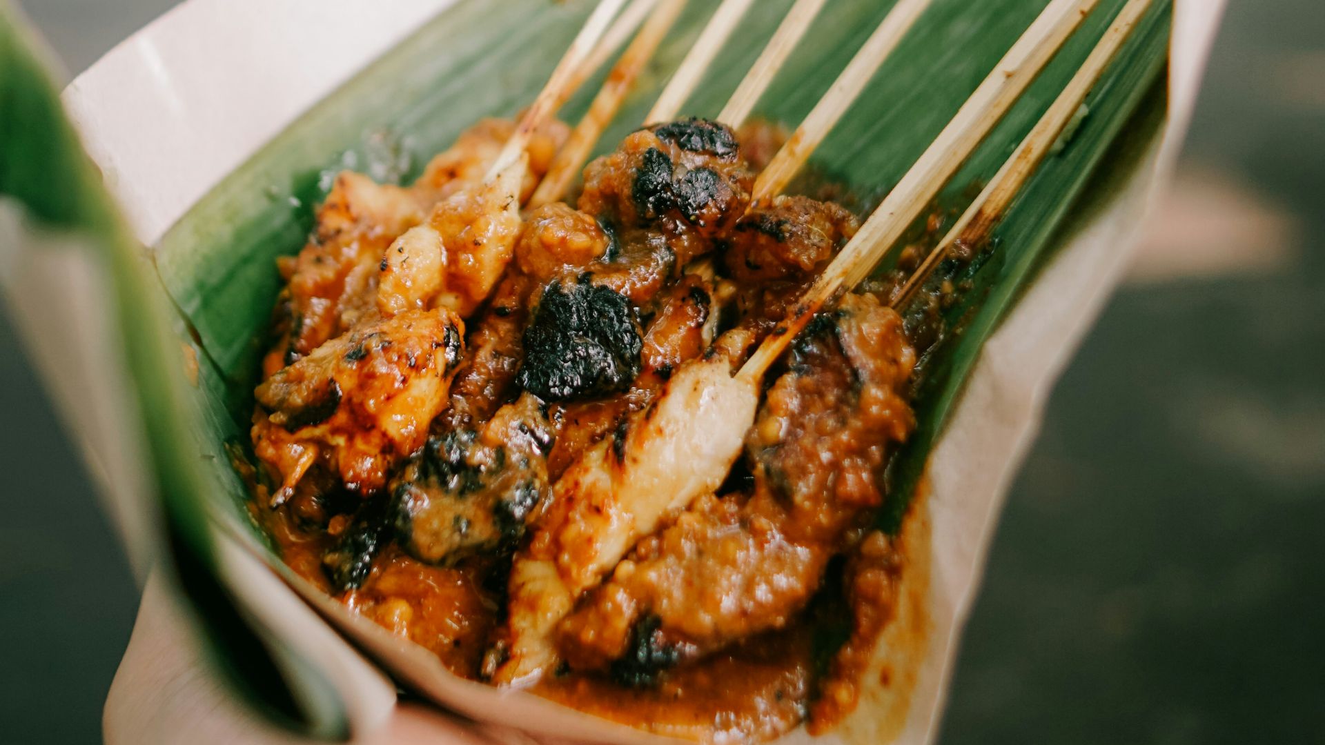 a person holding a plate of food with chopsticks