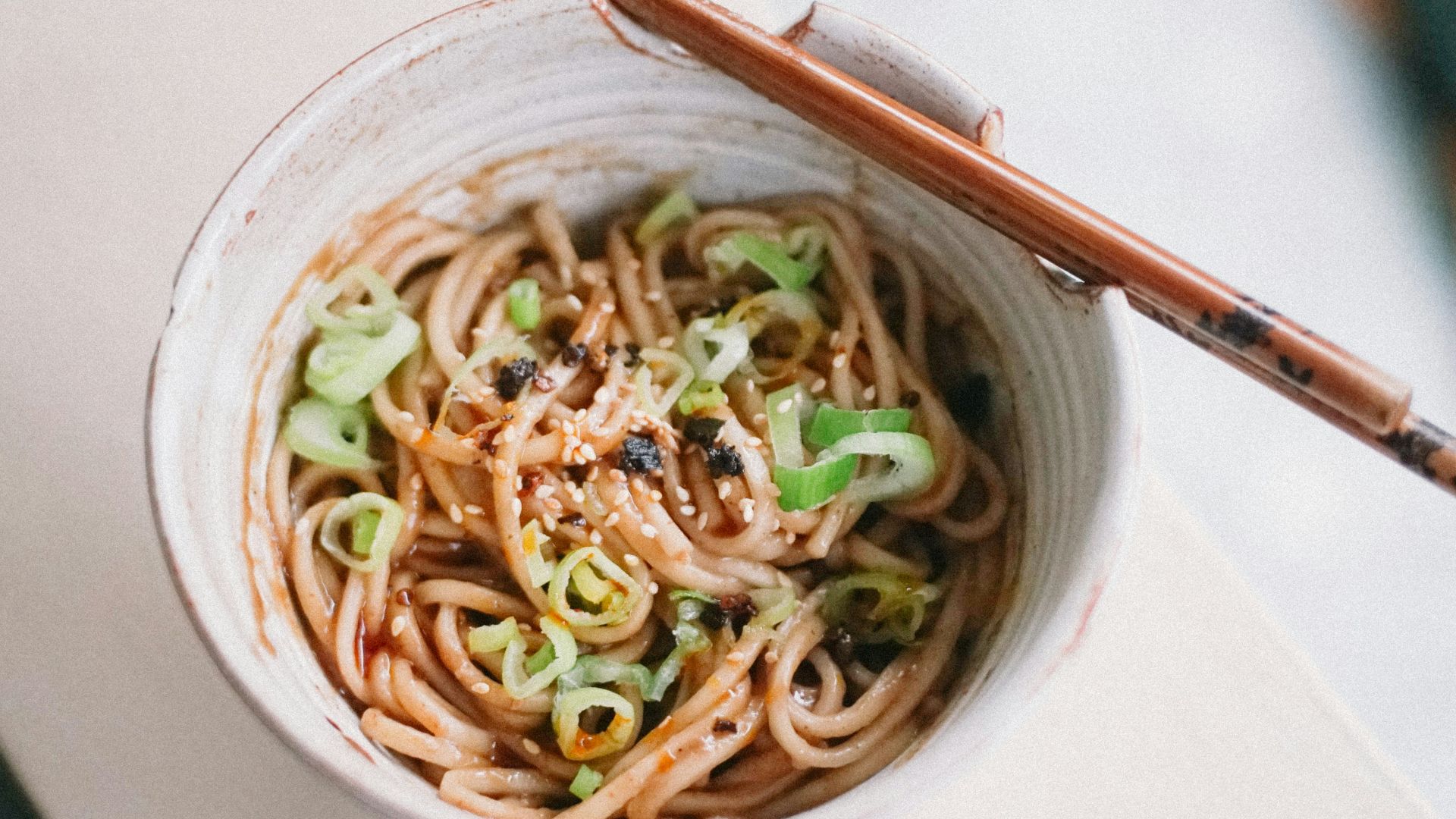 white ceramic bowl with noodles and chopsticks