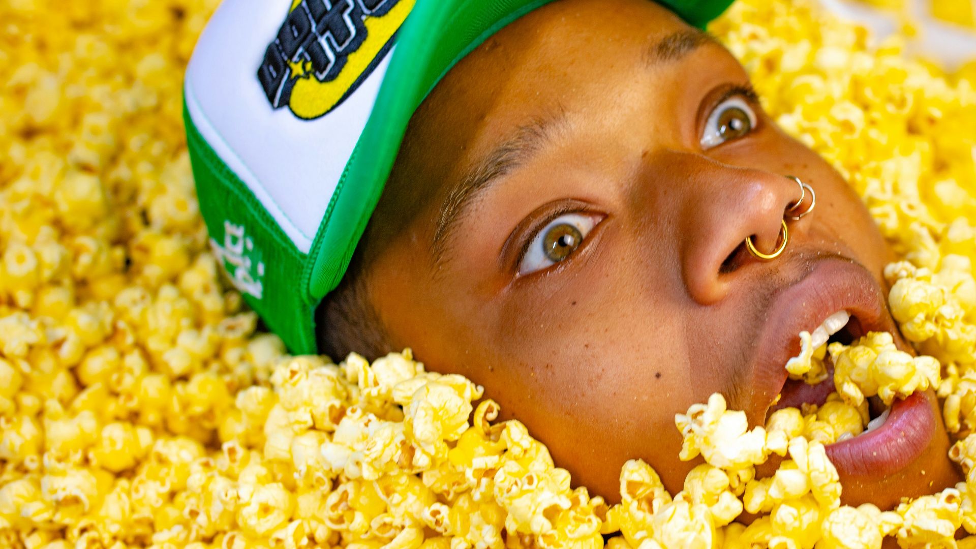 a man with a green hat is in a pile of popcorn