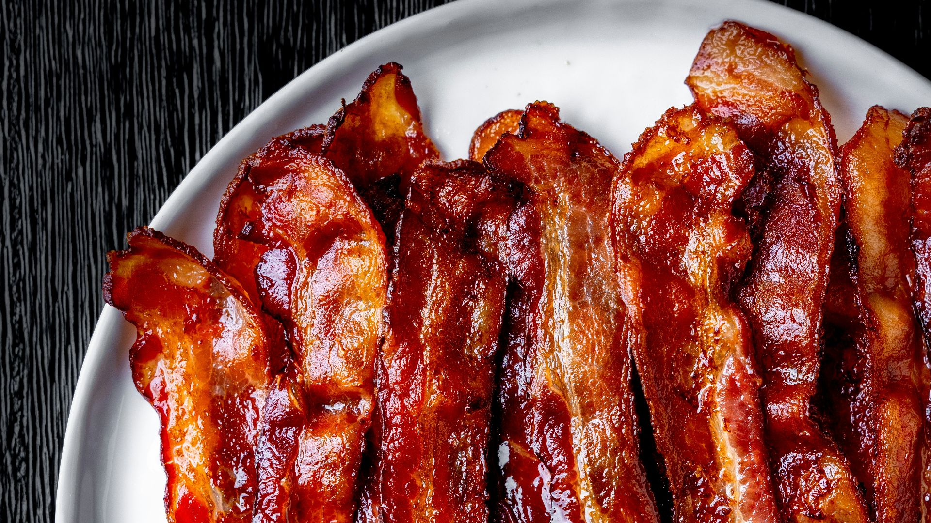 a white plate topped with bacon strips on top of a table