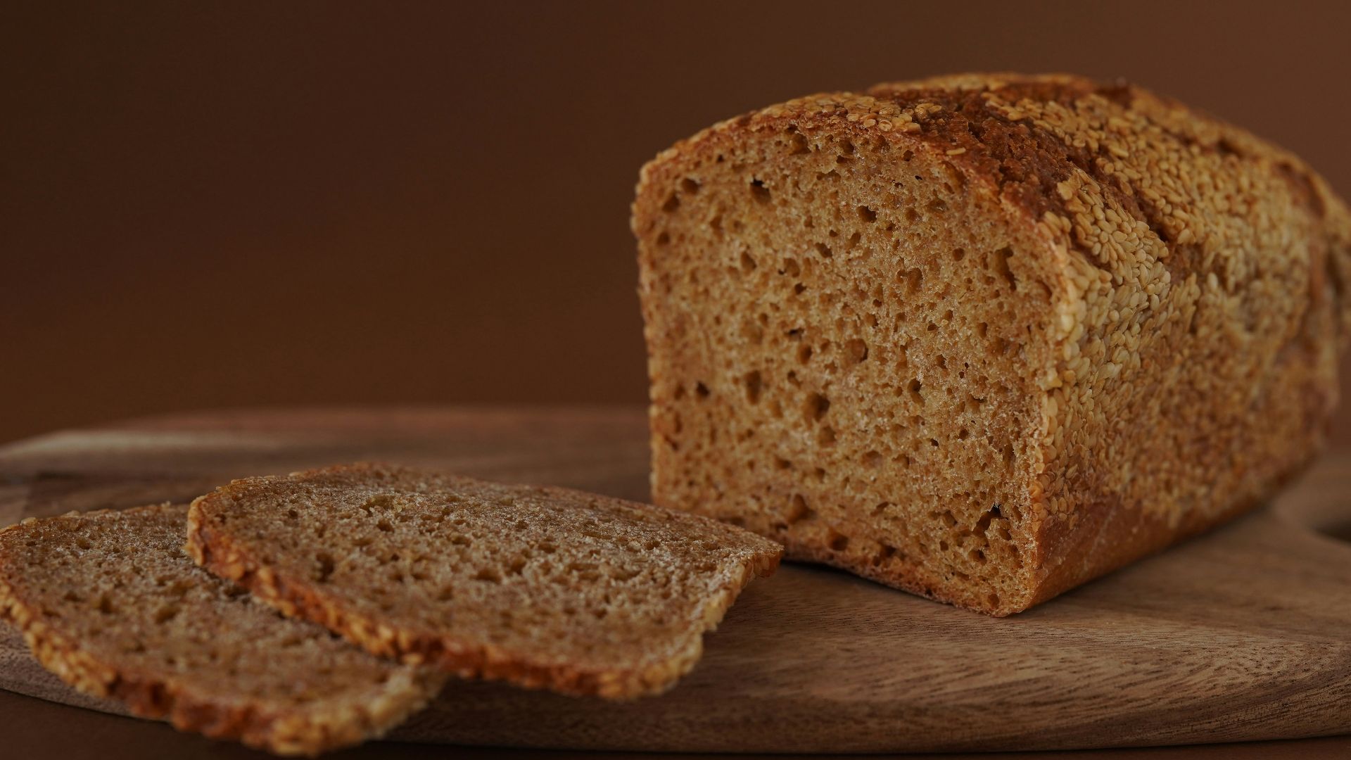 Bread loaf and slices on a wooden board.