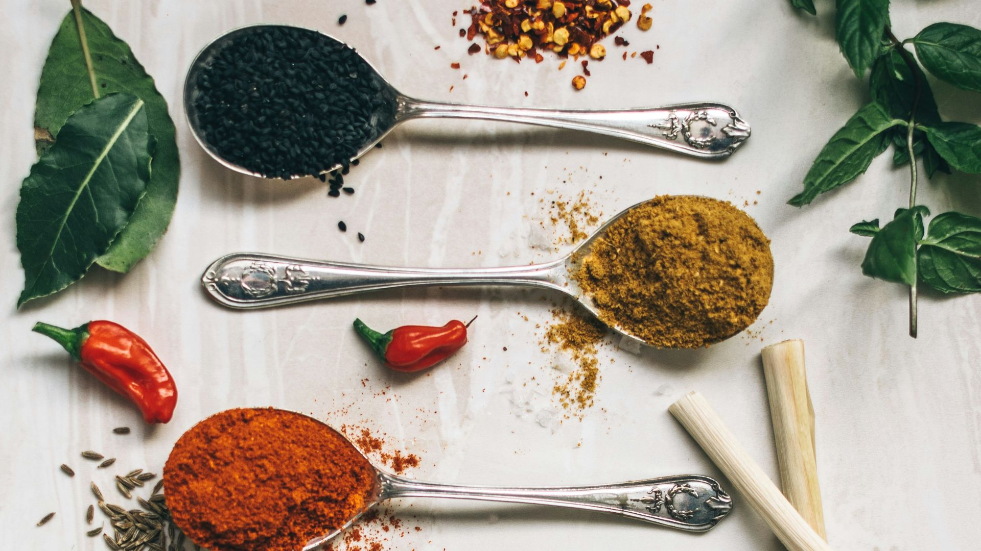 five gray spoons filled with assorted-color powders near chilli