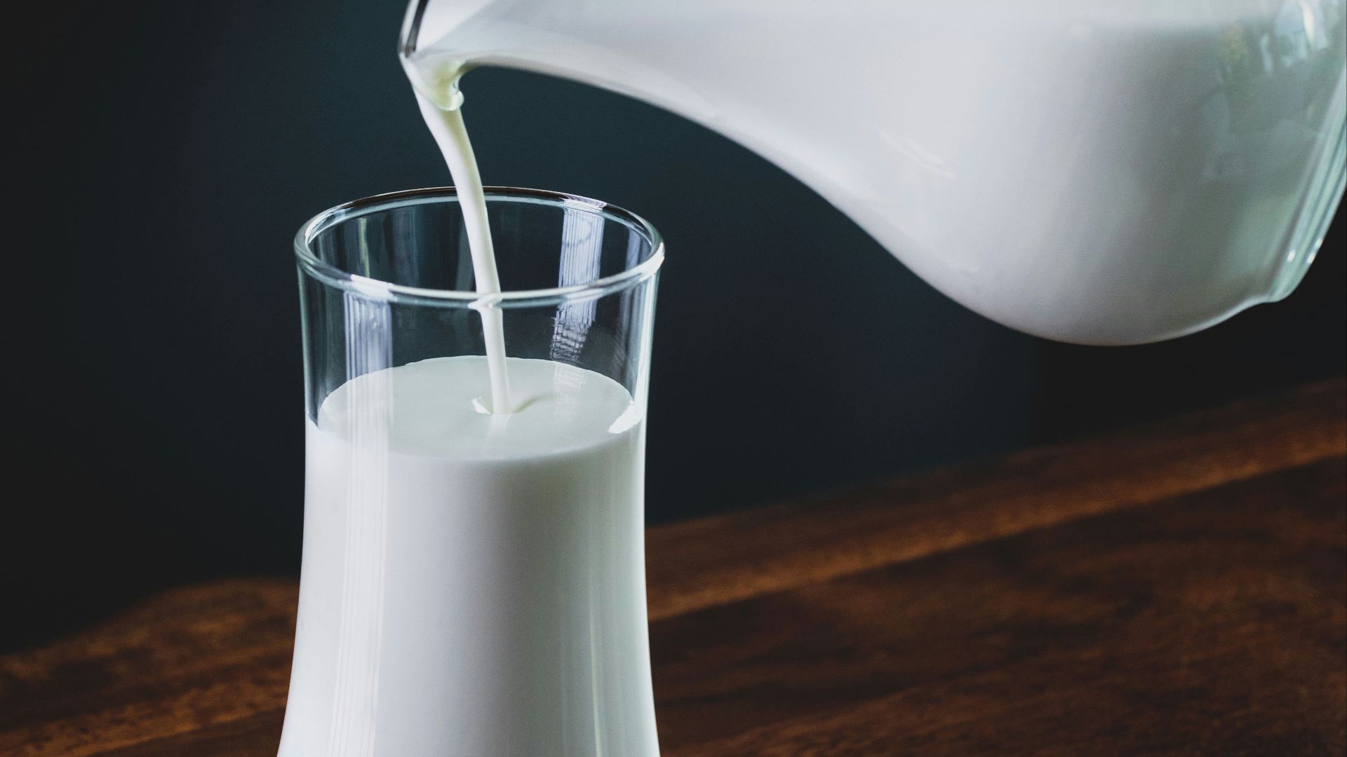 person pours milk into glass