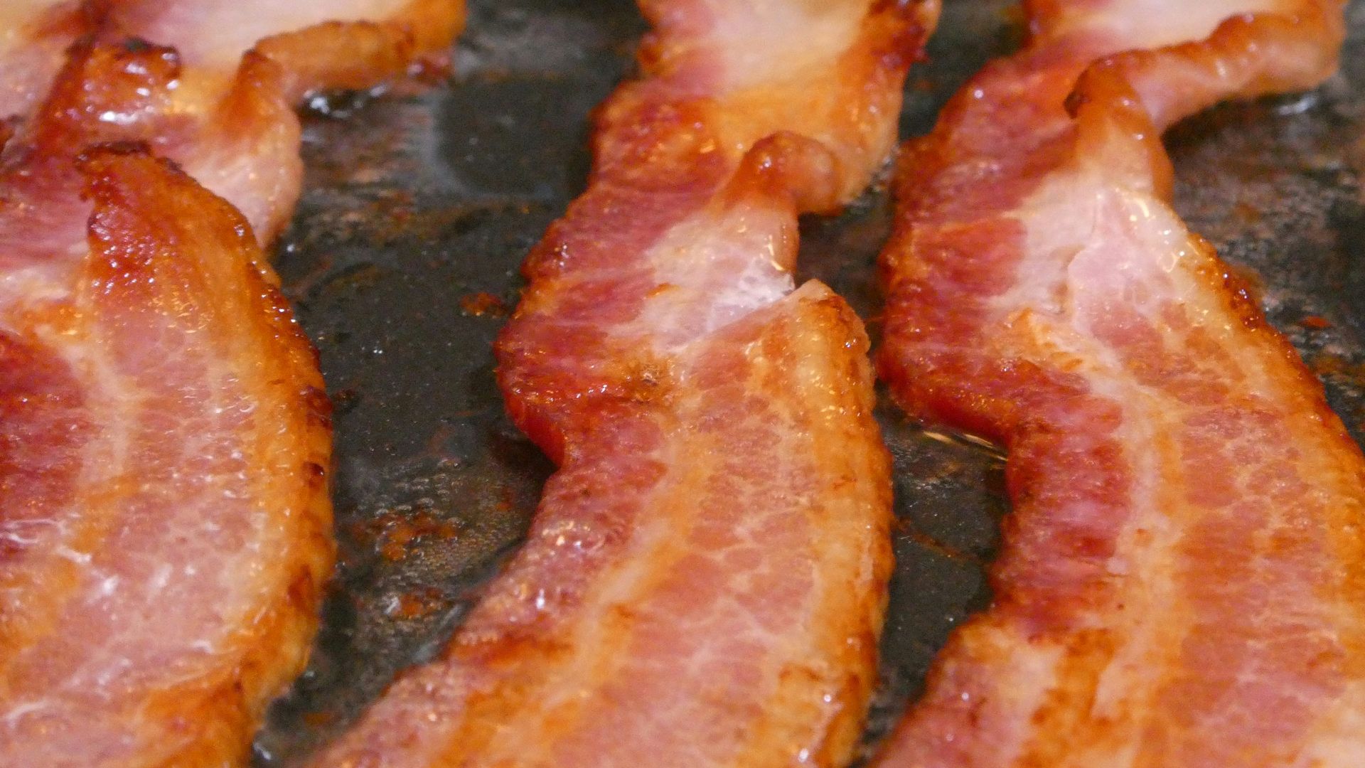 bacon is being cooked in a frying pan