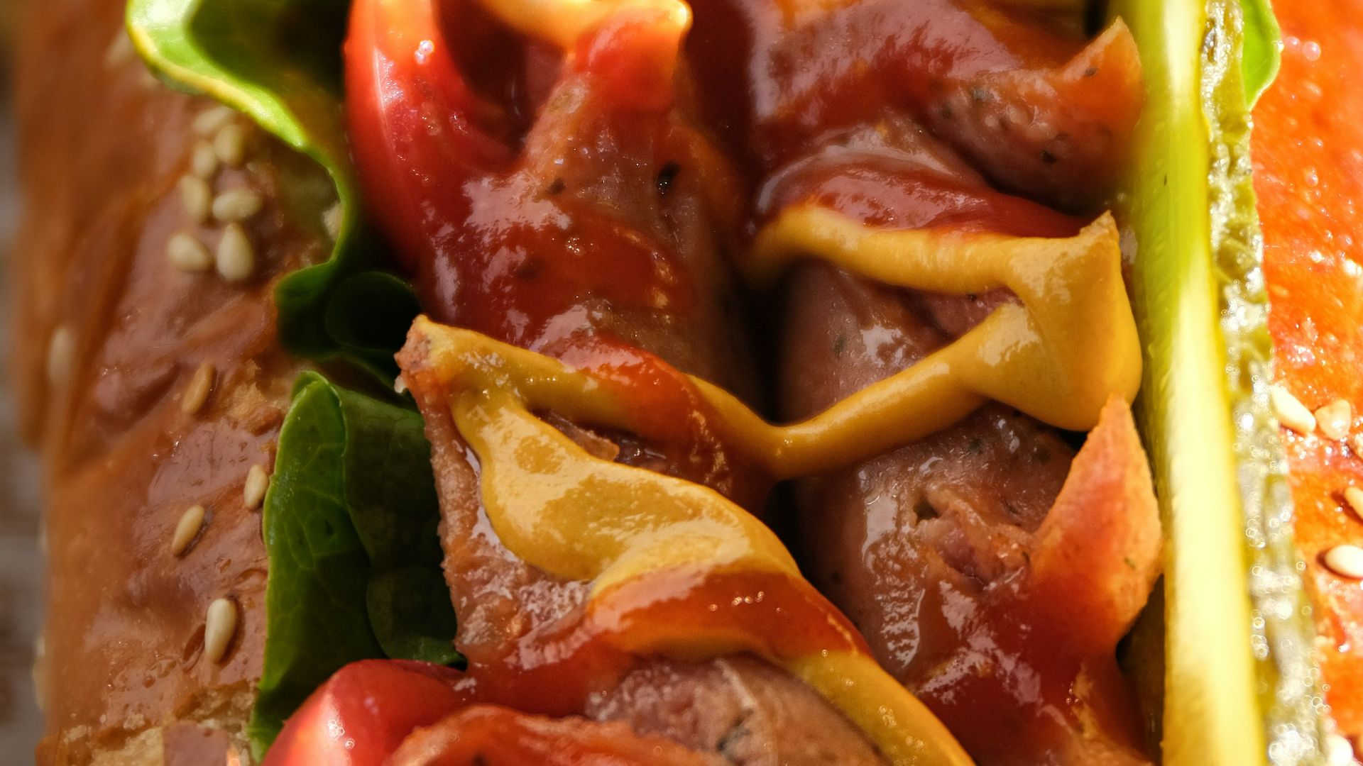 a hot dog with tomatoes, lettuce, and mustard