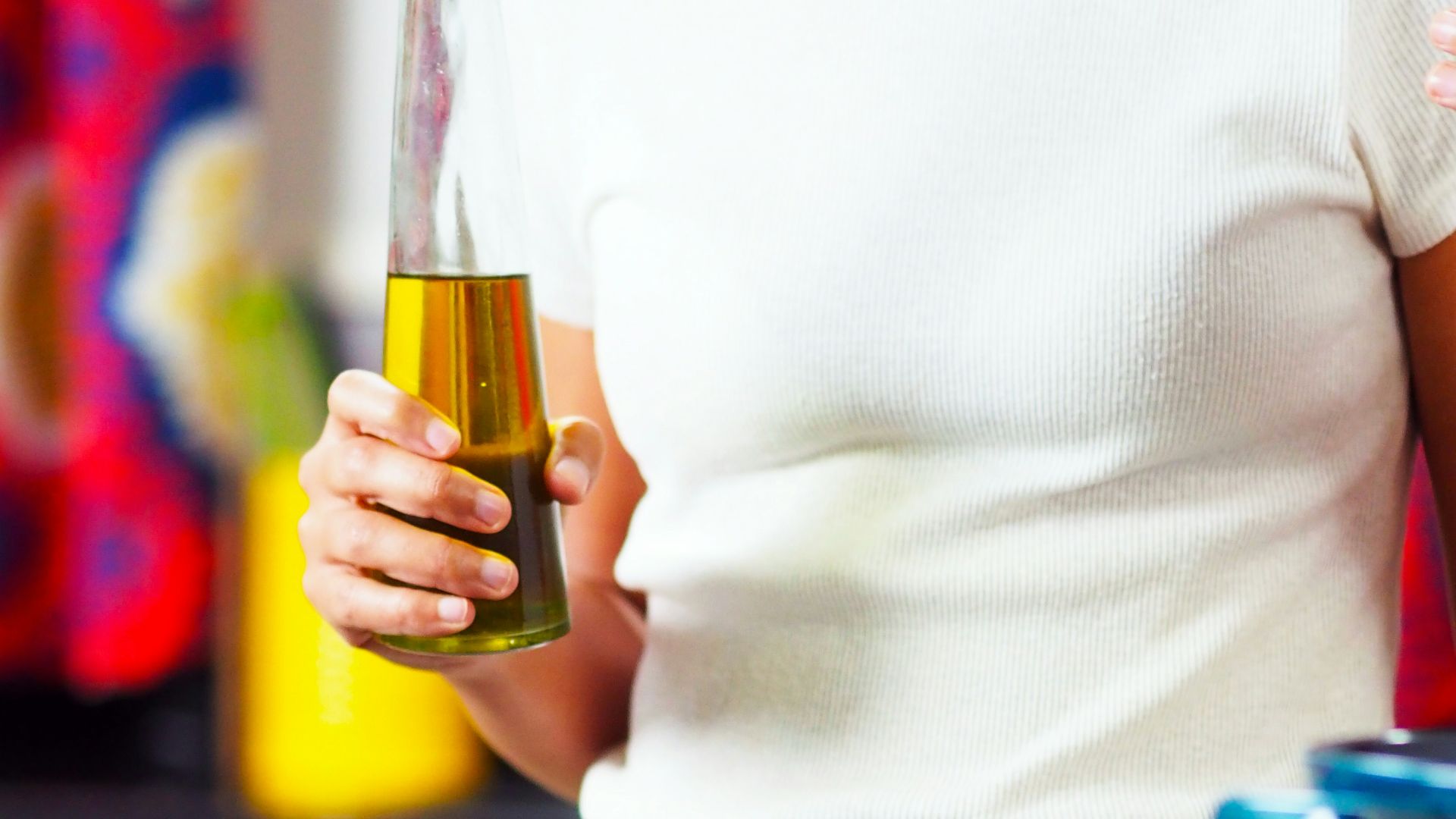 person holding bottle of oil at gas stove