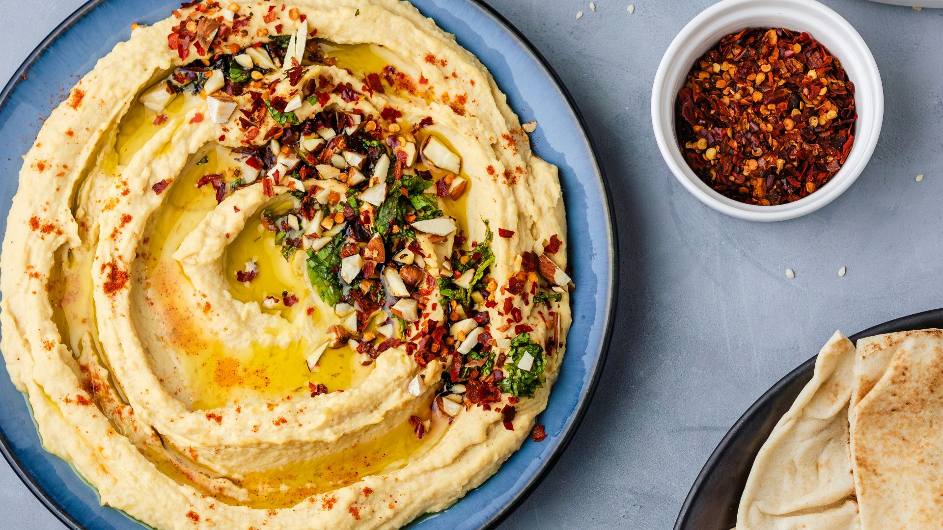 a plate of hummus, pita bread, and a bowl of olive oil