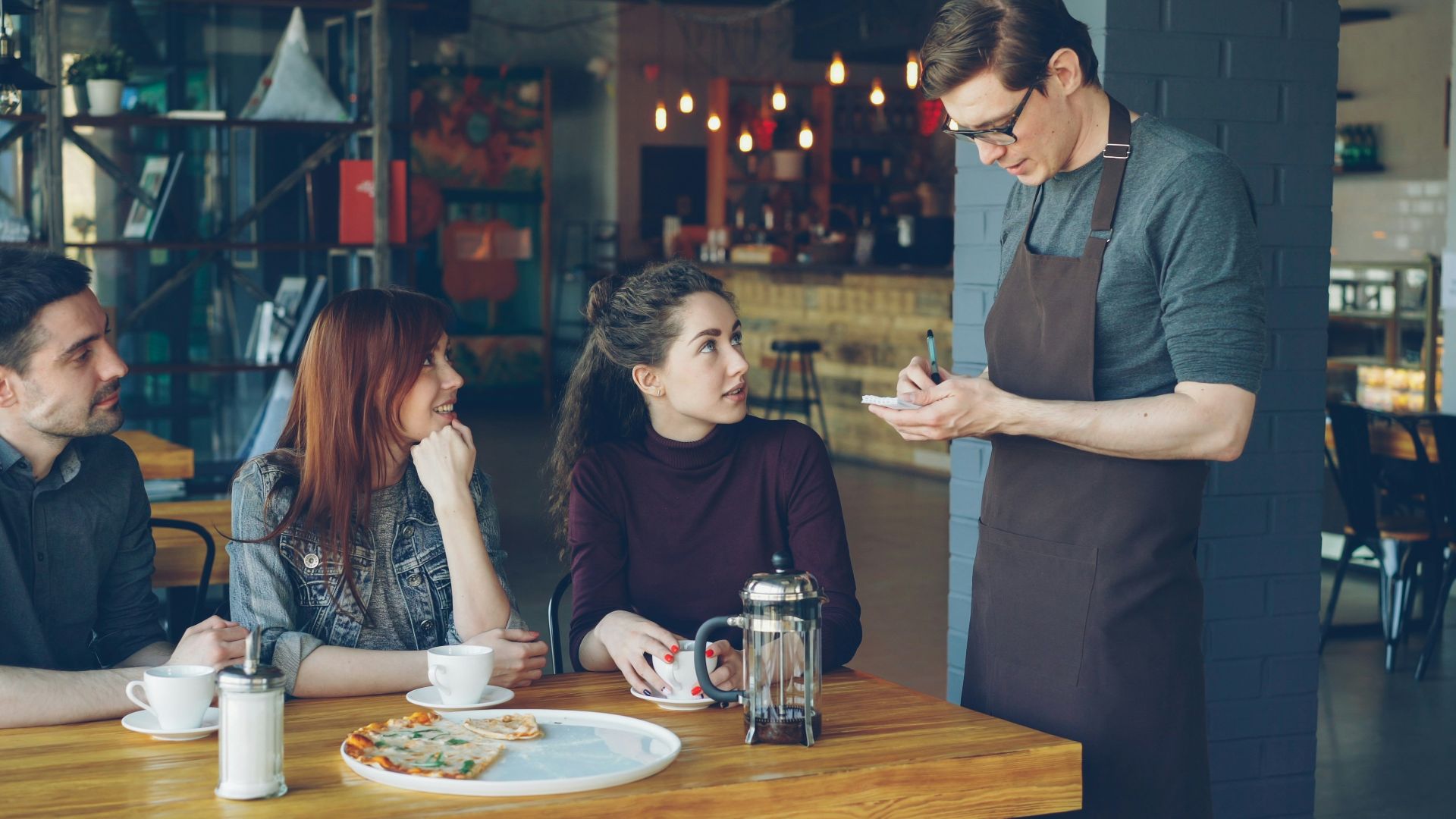 A waiter takes an order from customers at a cafe.