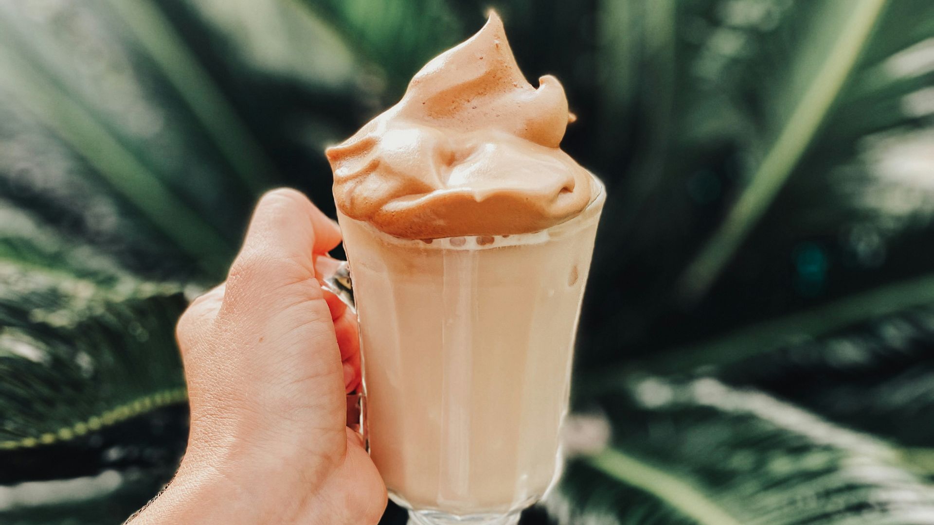 person holding clear glass cup with brown liquid
