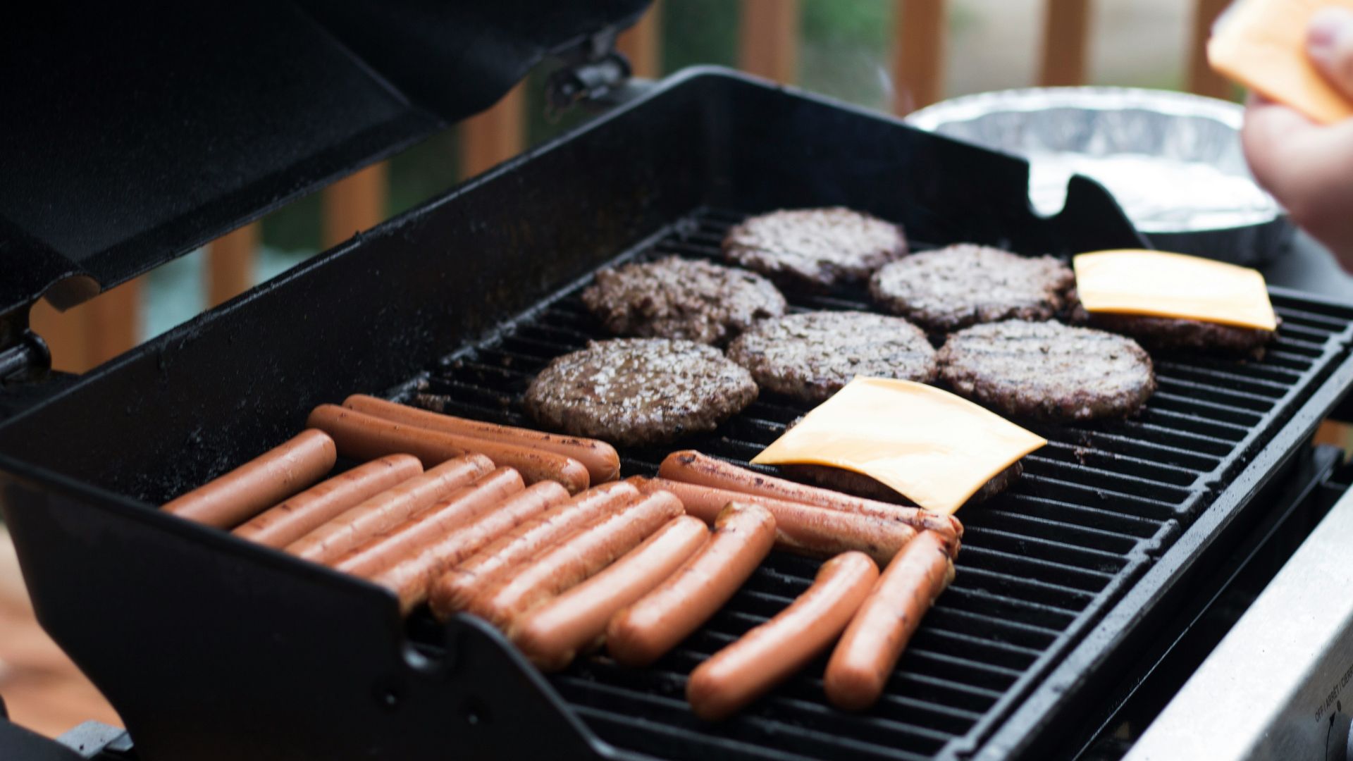 person standing in front grill grilling sausage
