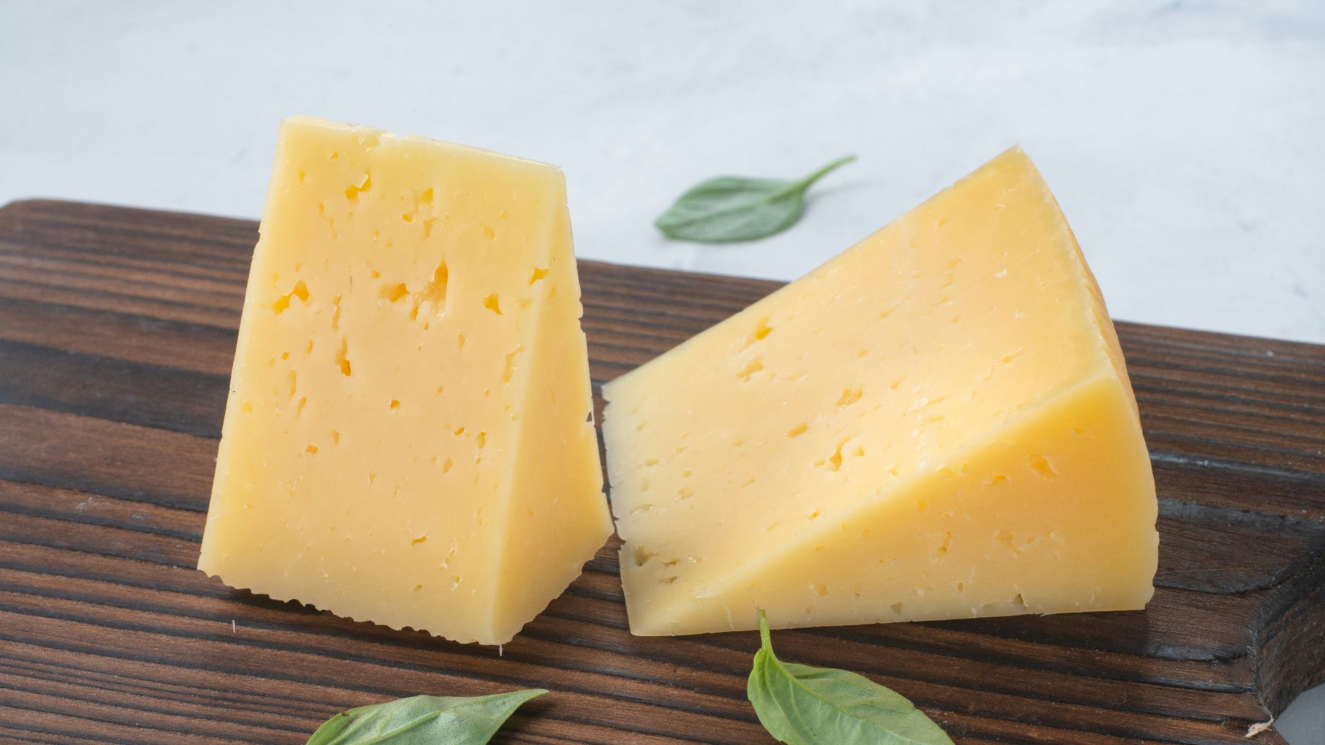 a couple of pieces of cheese sitting on top of a wooden cutting board