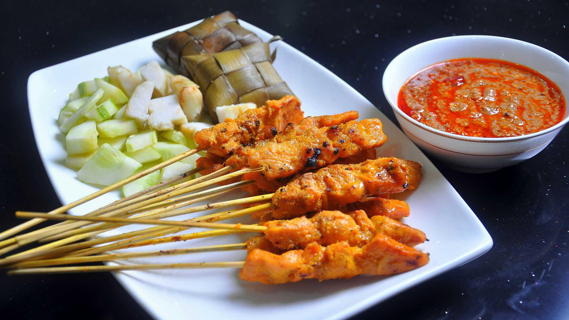 a white plate topped with meat and veggies next to a bowl of sauce