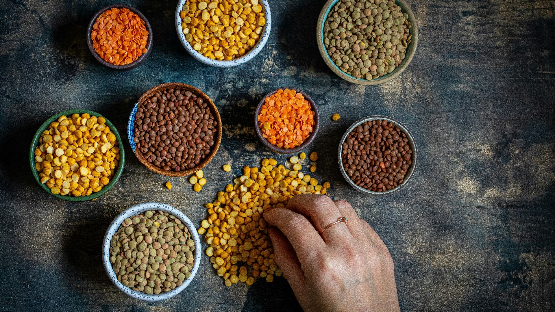 a person touching a bowl of lentils on a table
