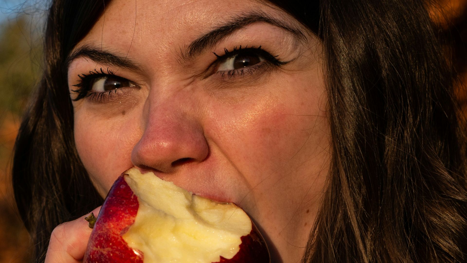 woman in gray sweater holding sliced of apple