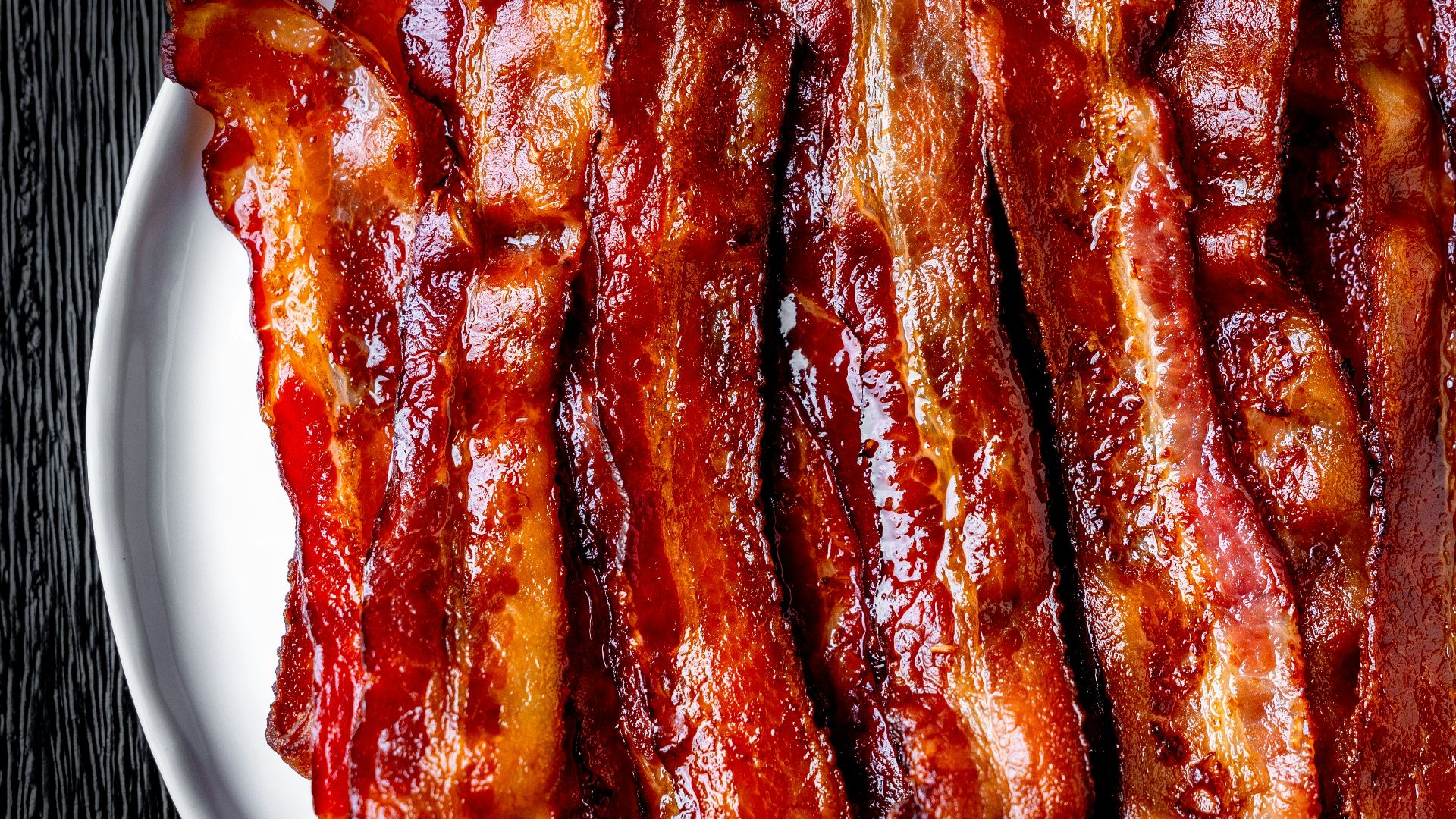 a white plate topped with bacon strips on top of a table