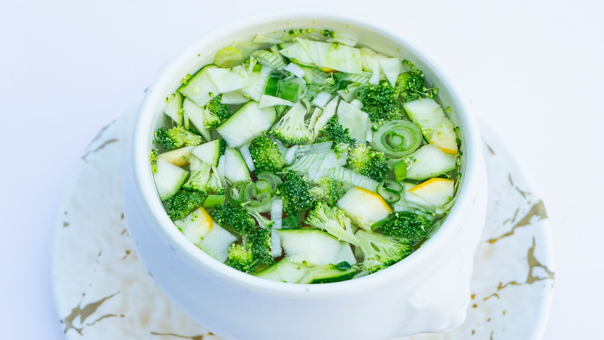 a white bowl filled with broccoli and cucumbers
