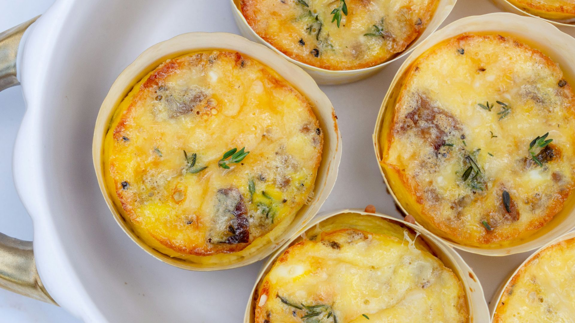 a white plate topped with mini quiches covered in cheese