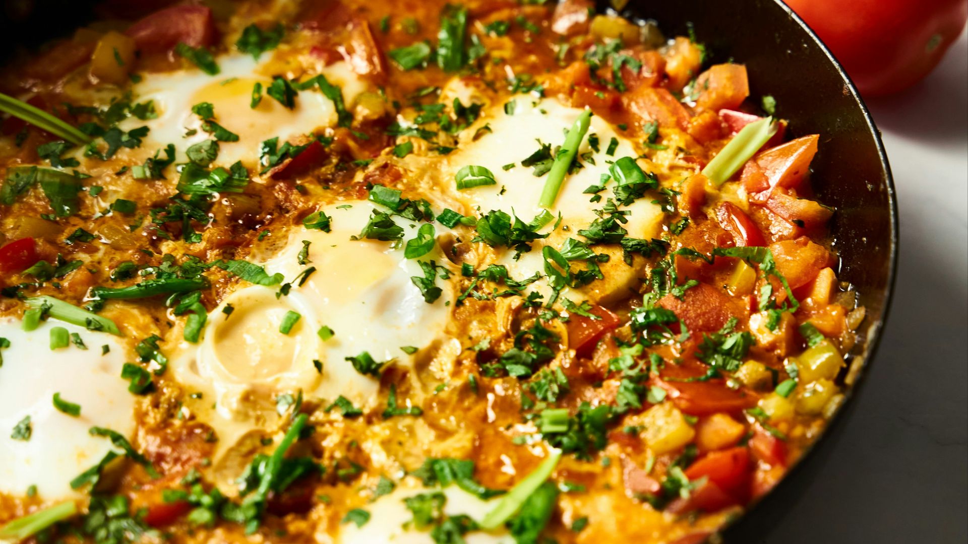 a skillet with eggs and tomatoes on a table