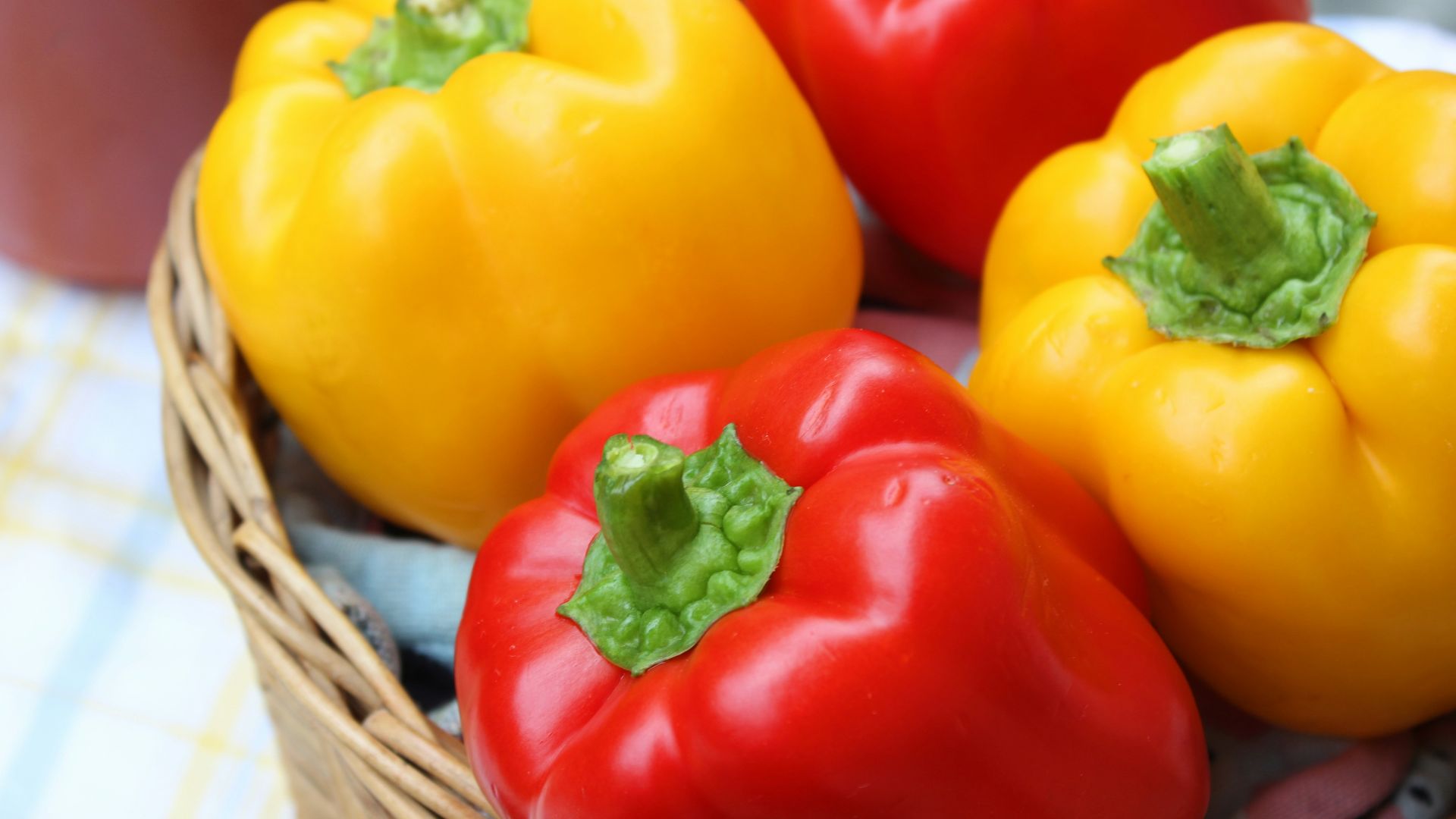 red and yellow bell peppers in brown woven basket