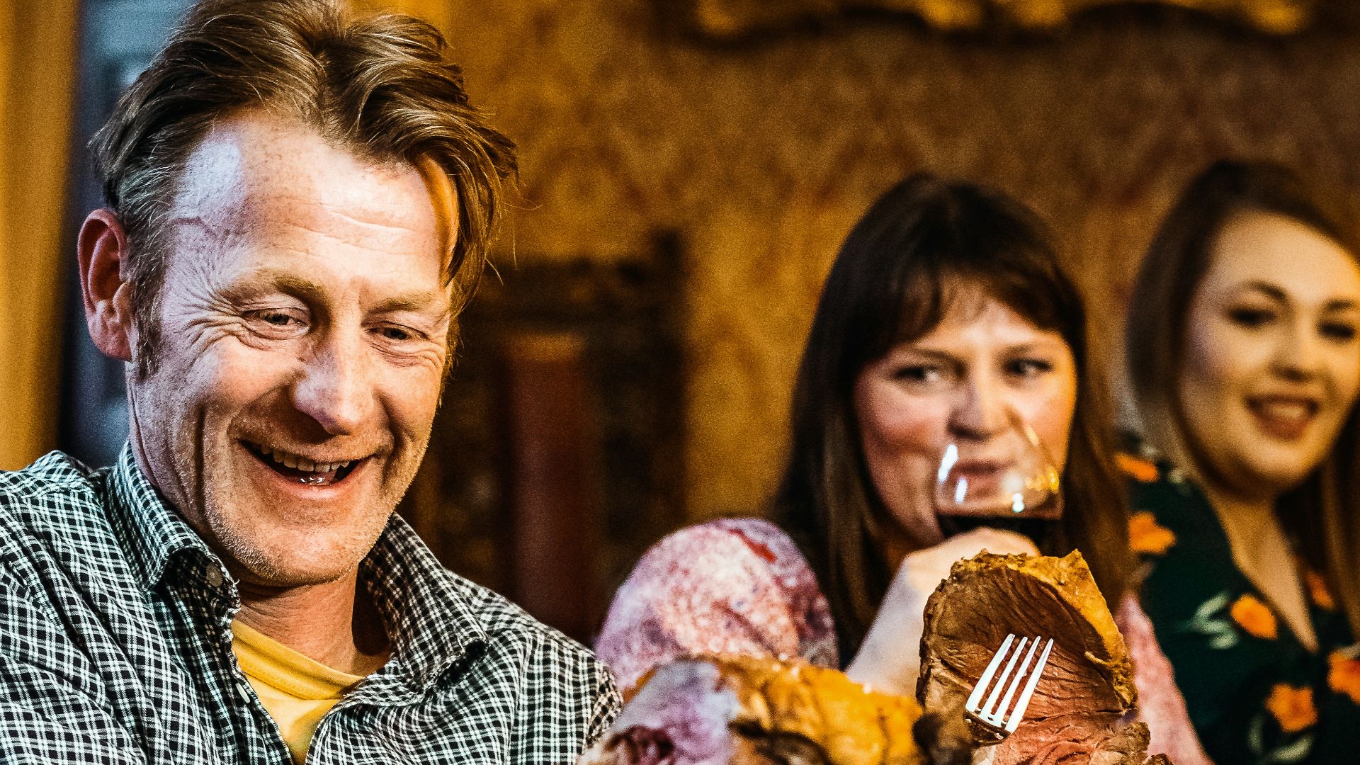 man in blue and white checkered button up shirt holding bread