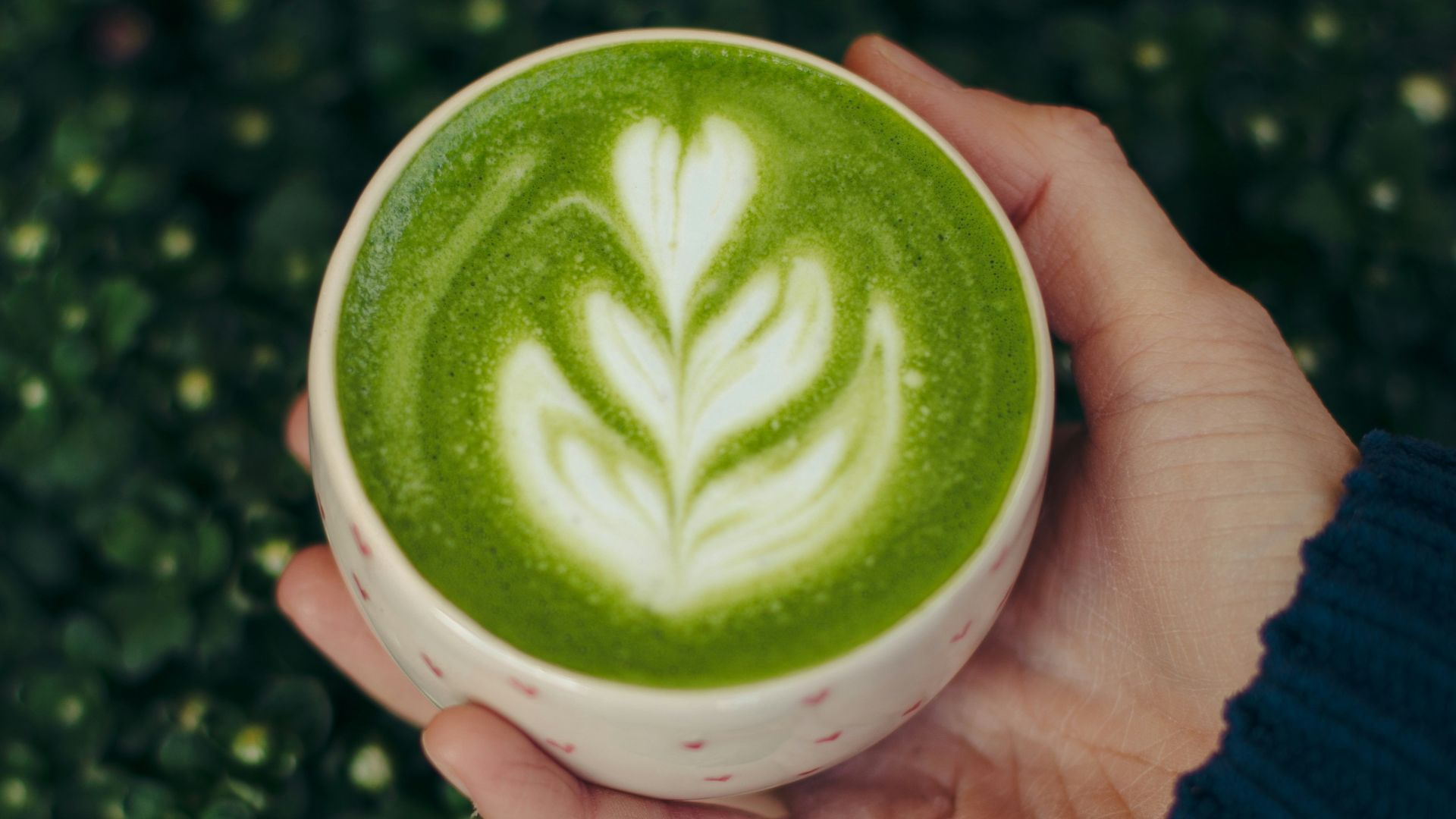A person holding a cup of green liquid