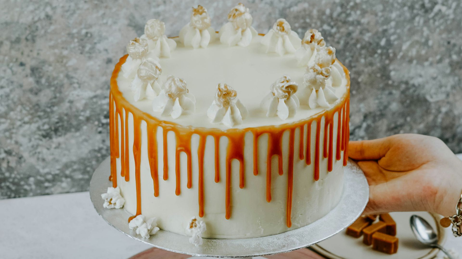person holding round white coated cake